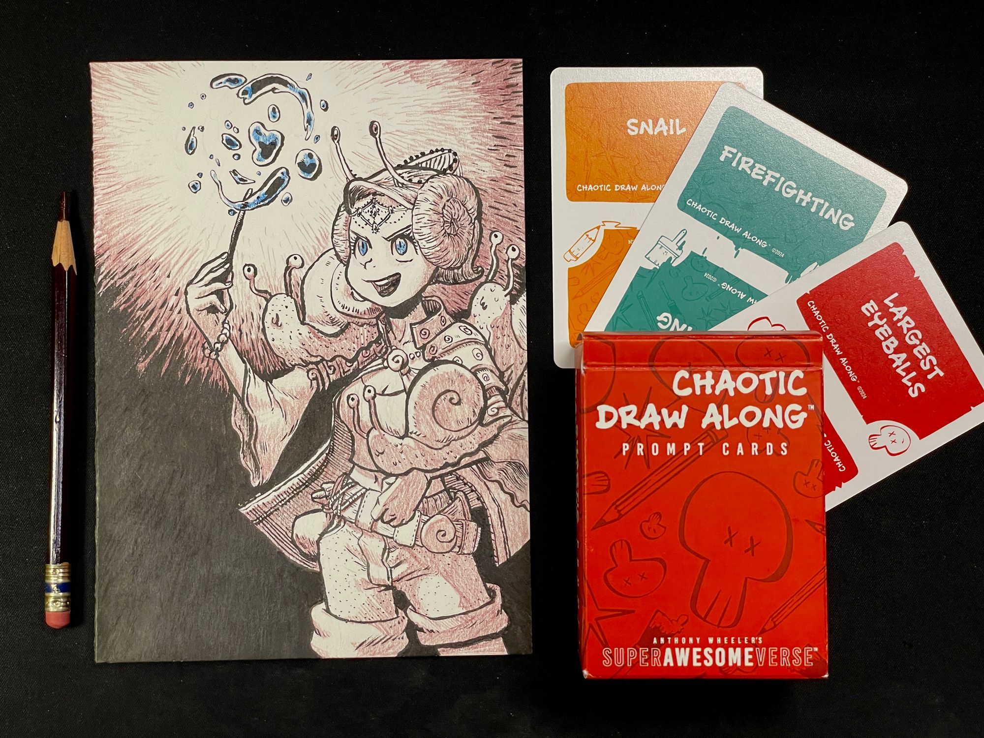 A photo of the previous drawing, next to a color pencil to the left, with three cards and a deck box on the right. Each card lists a prompt, reading, "snail", "firefighting", and "largest eyeballs" respectively. The deck box reads, "Chaotic Draw Along - Prompt Cards"