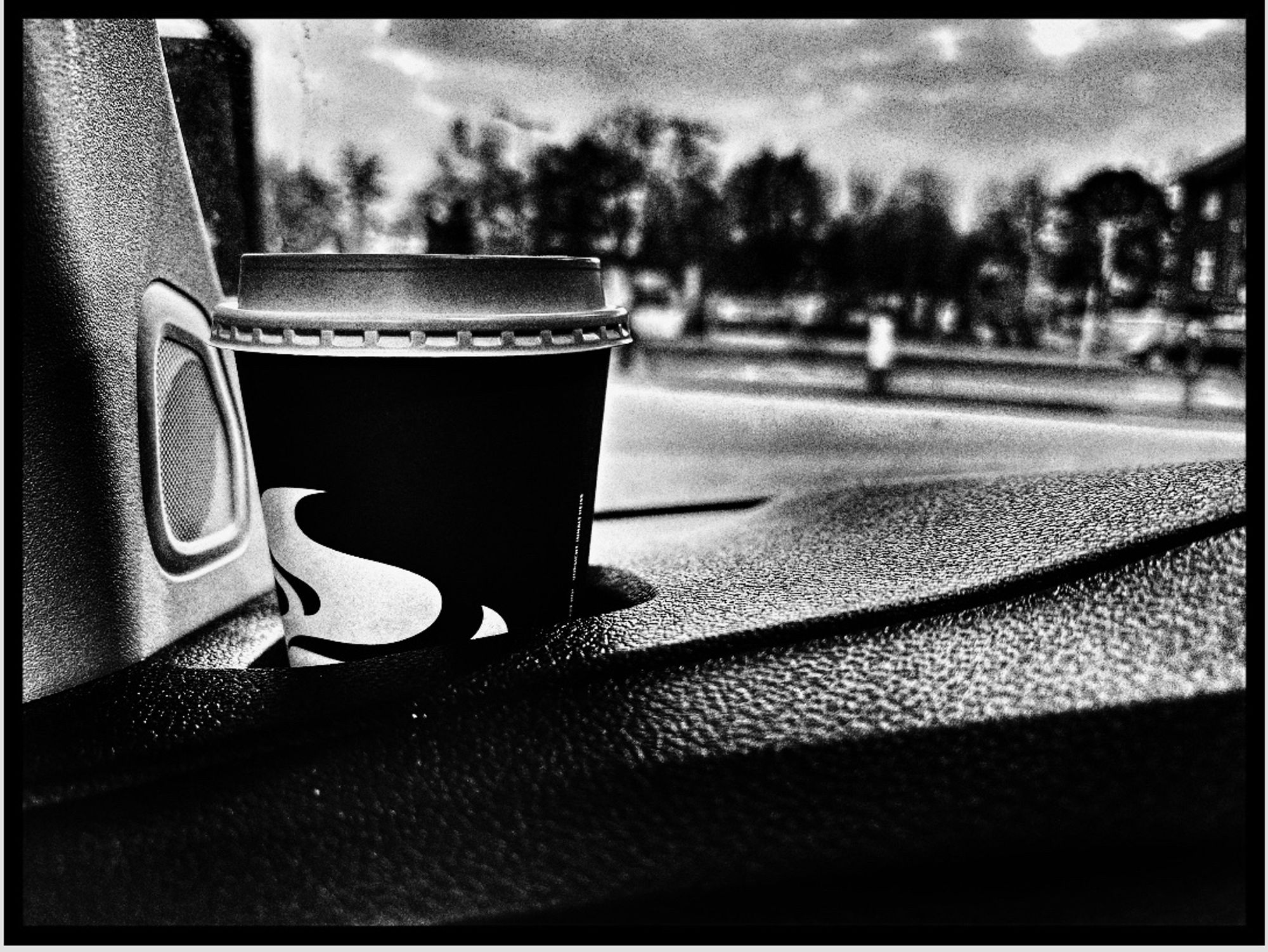 Schwarz-Weiß-Foto eines Kaffebechers im Auto .