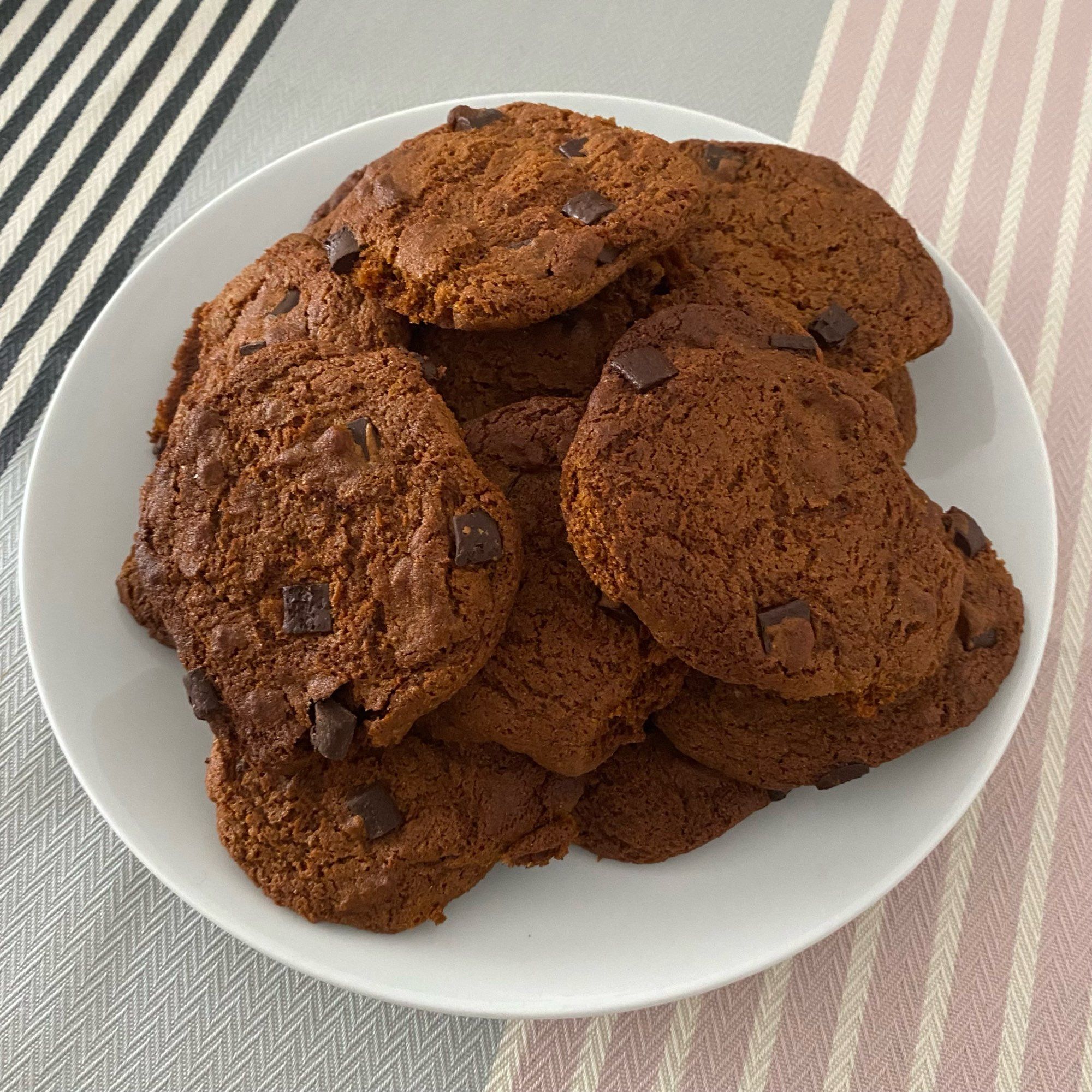 Tas de cookies à la châtaigne d’après la recette du livre d’OwiOwi. Sur une assiette blanche ronde. En arrière plan une nappe grise, avec des rayures roses et noires.