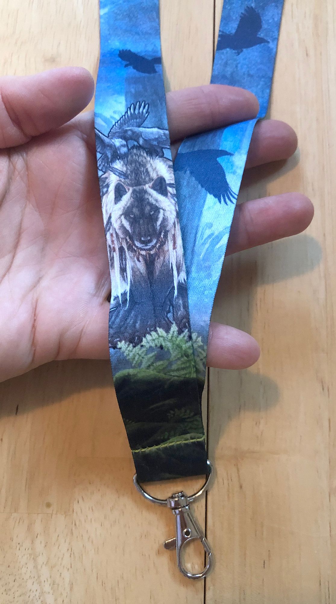 Photo of a lanyard in a hand with a werewolf and some ravens printed on it