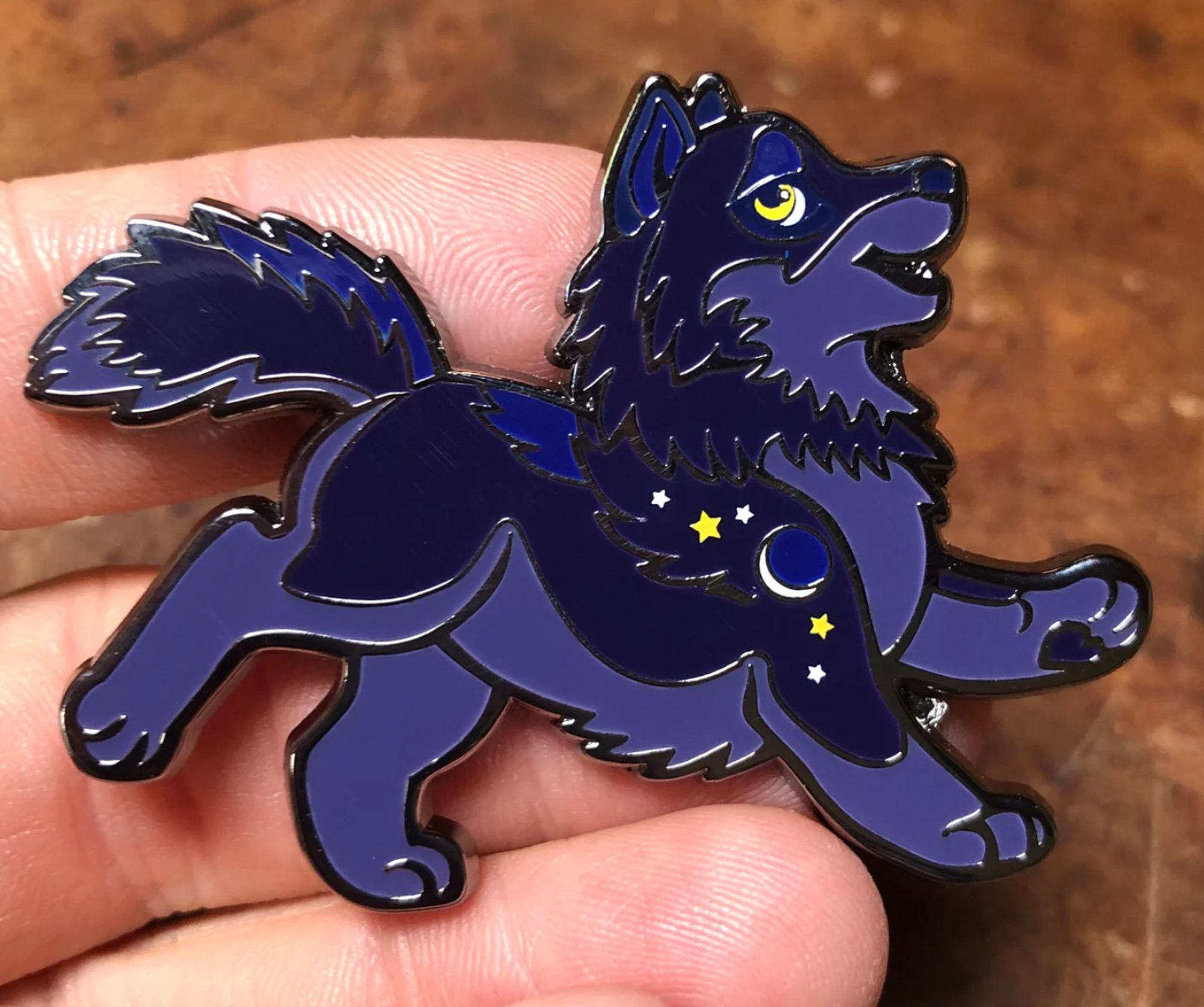 Enamel pin of a dark purple chibi cartoon wolf