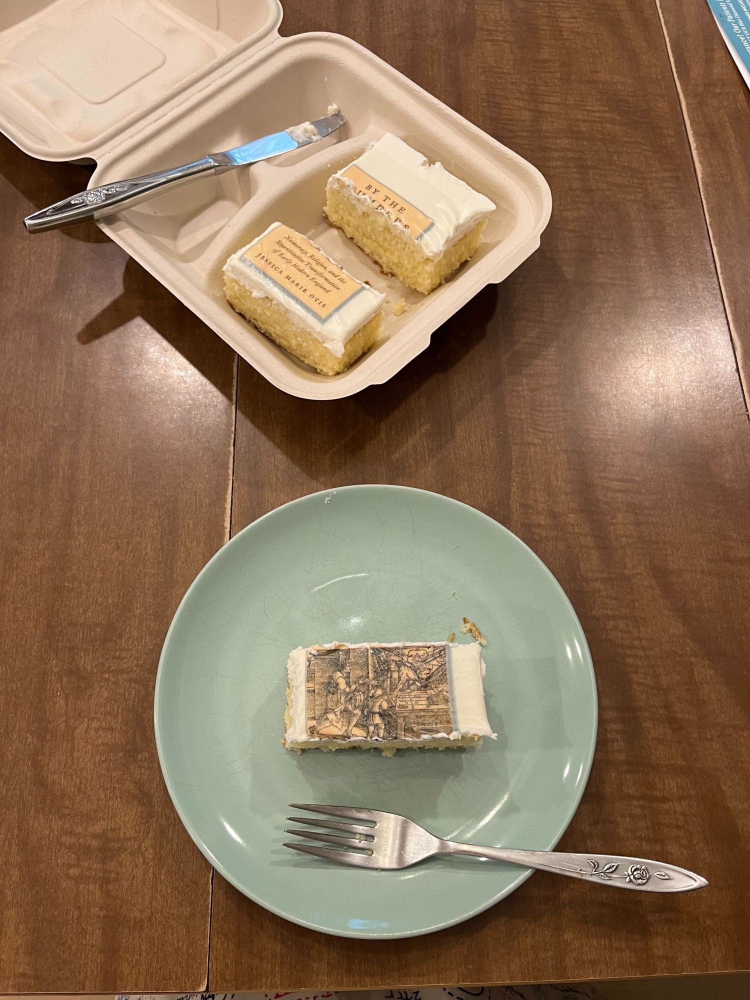 a piece of cake with a book cover on it - the middle part with the historical image has been sliced out and is sitting on a plate with a fork