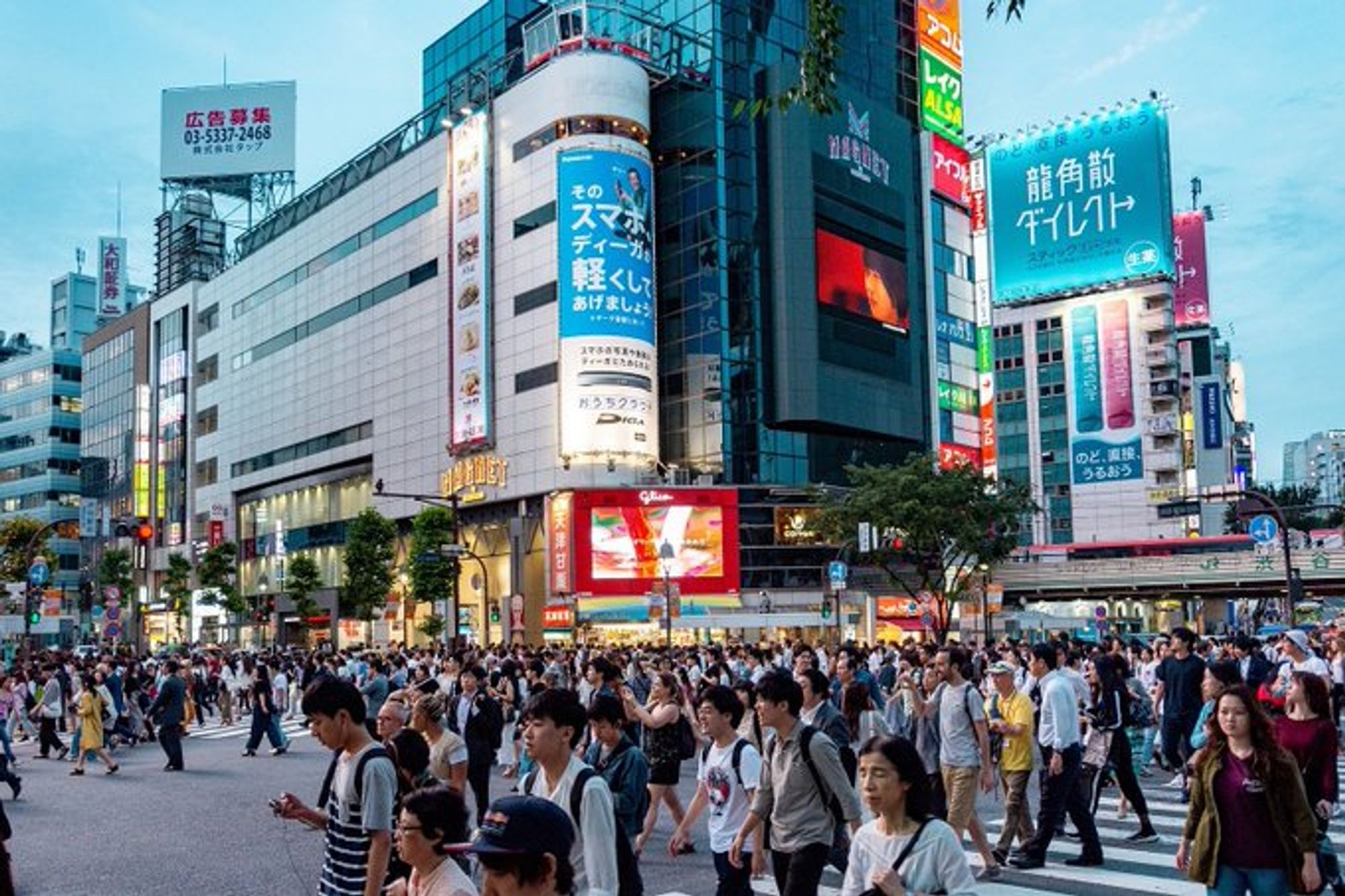 Crowds of people walk in a busy Japanese street.