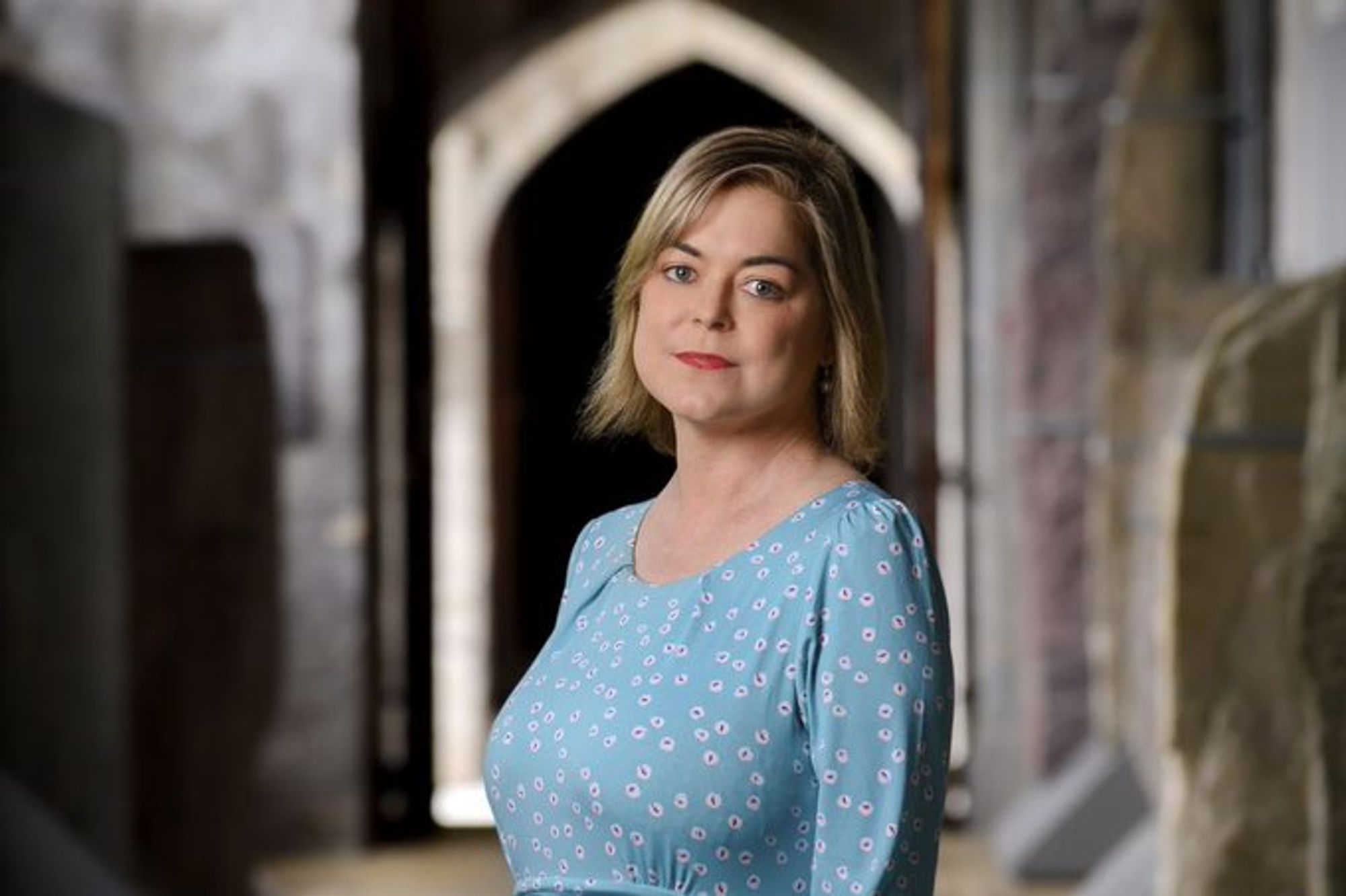 Professor Louise Crowley stands in the stone corridor of UCC's Quad.