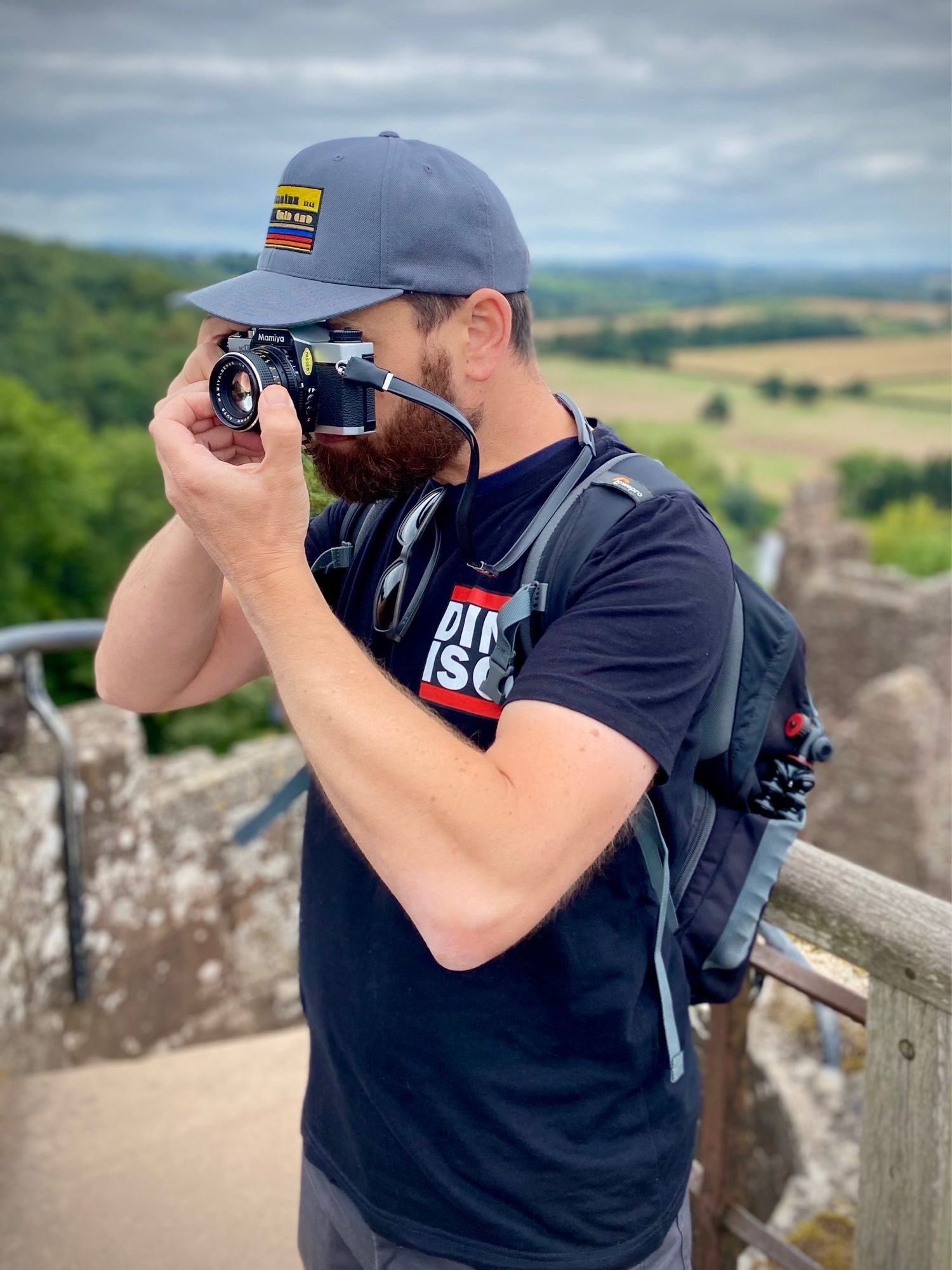 Me aiming a camera at something, on a bit of castle, wearing the t-shirt I’m trying to flog