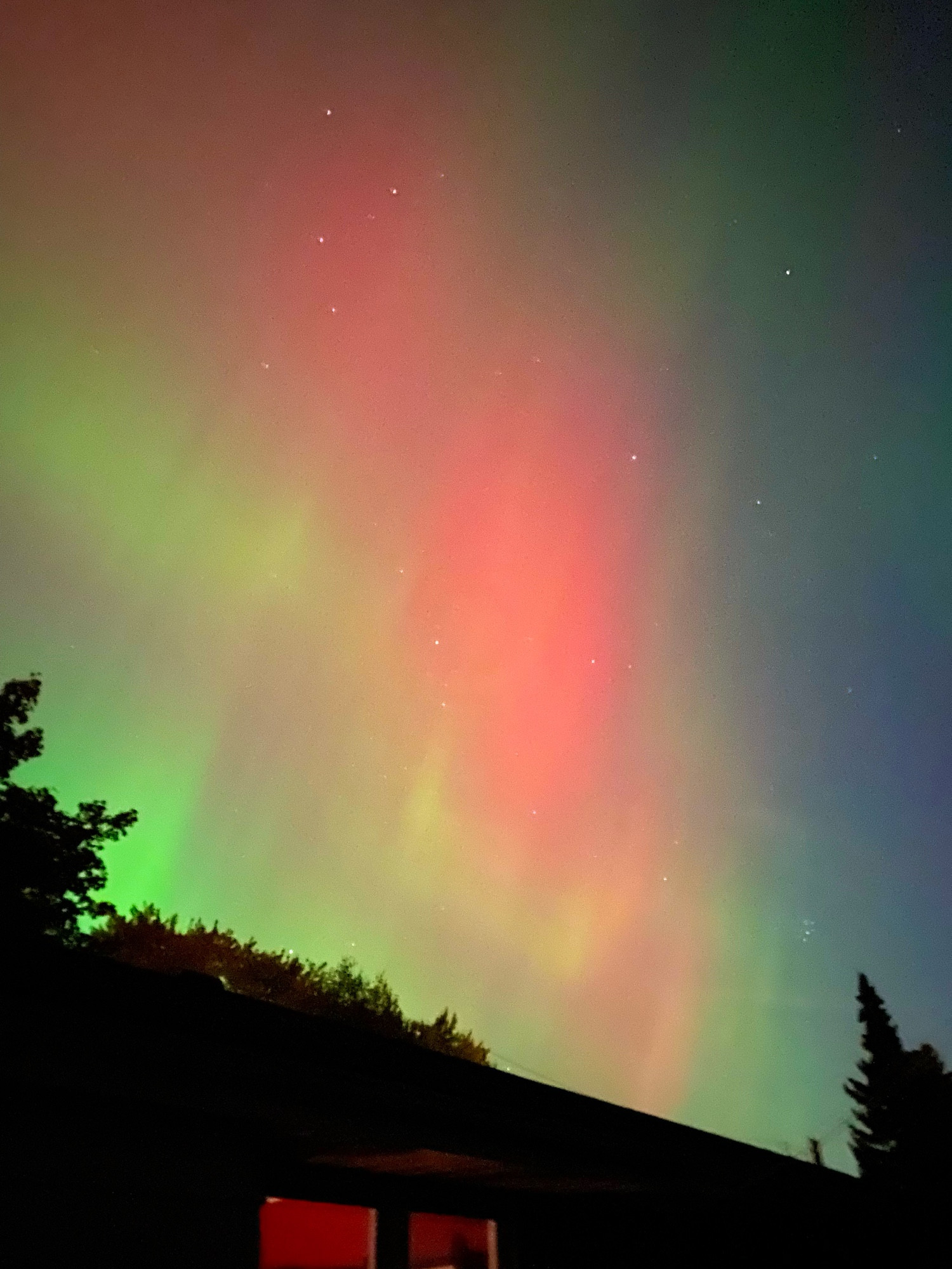 Northern lights over a house of reds, hello and green. 