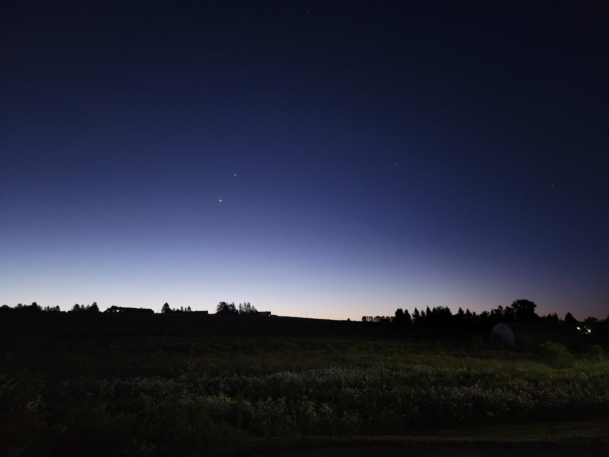 A late night or early dawn landscape.  Dark foreground. Venus and Jupiter in conjunction above the horizon. The constellation Orion dimly visible to the right.