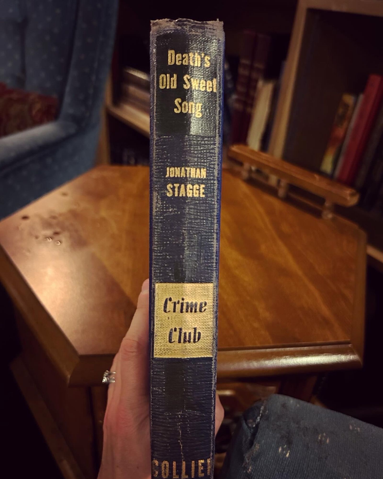 A photo of the spine of the book “Death’s Old Sweet Song” by Jonathan Stagge. It’s from 1946 and looks it, bound in black and dark navy blue with gold embellishments and also has “Crime Club” indicating it may have been part of a set or maybe a subscription.