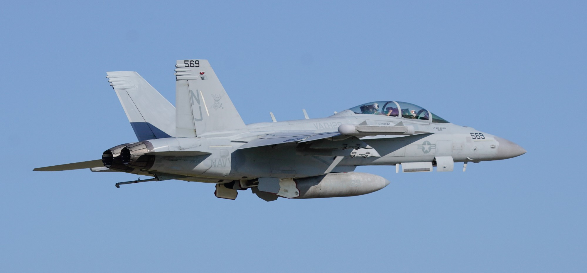 Right facing side profile of a US Navy EA-18G Growler showing the rear section and tail of the plane. 