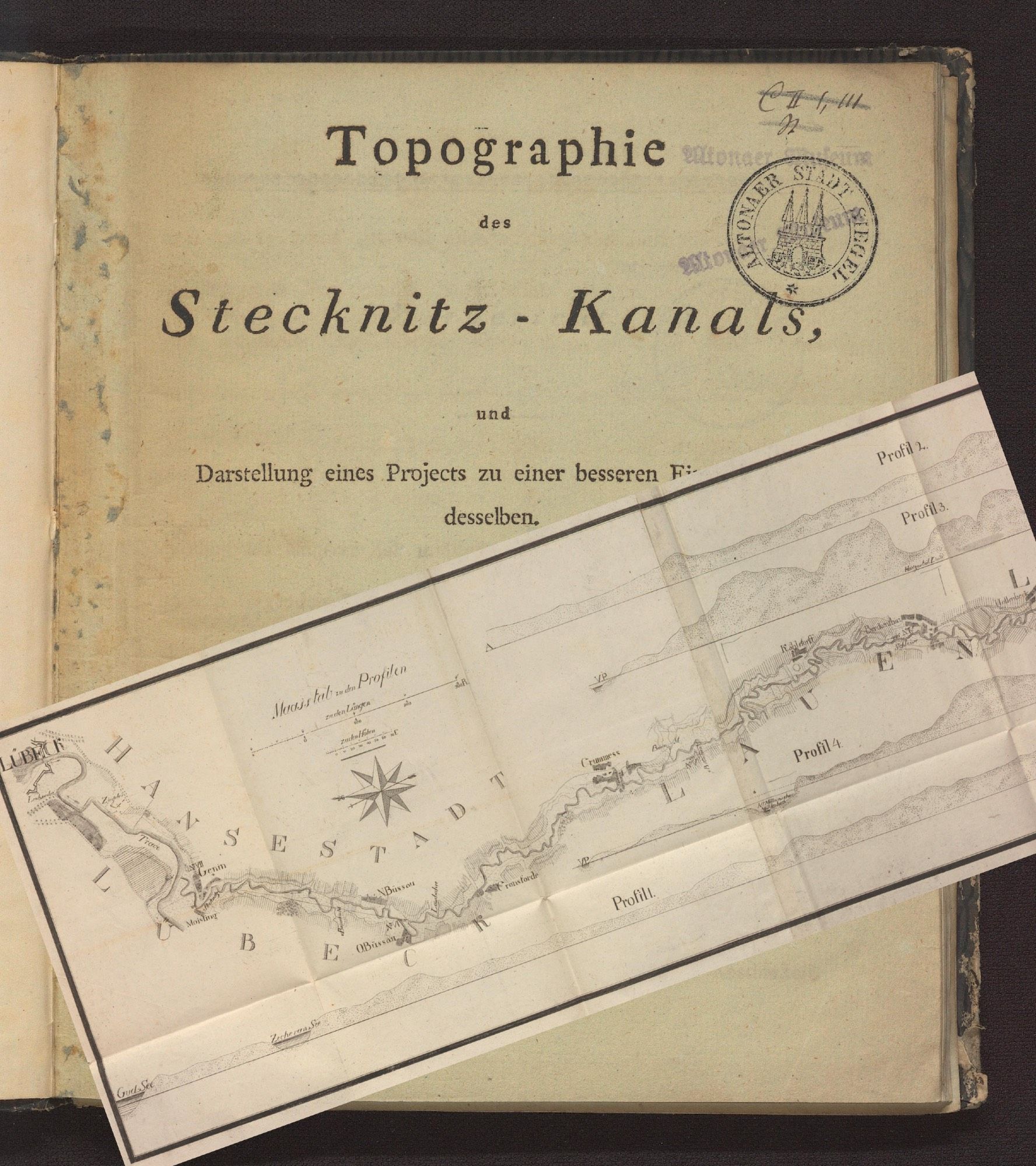 Das Bild zeigt ein altes Buch mit dem Titel "Topographie des Stecknitz-Kanals", mit einer dazugehörigen gefalteten Karte, die den Stecknitz-Kanal darstellt. Die Karte enthält verschiedene geografische Details und Profile, die die Route des Kanals und die zugehörigen Standorte angeben.