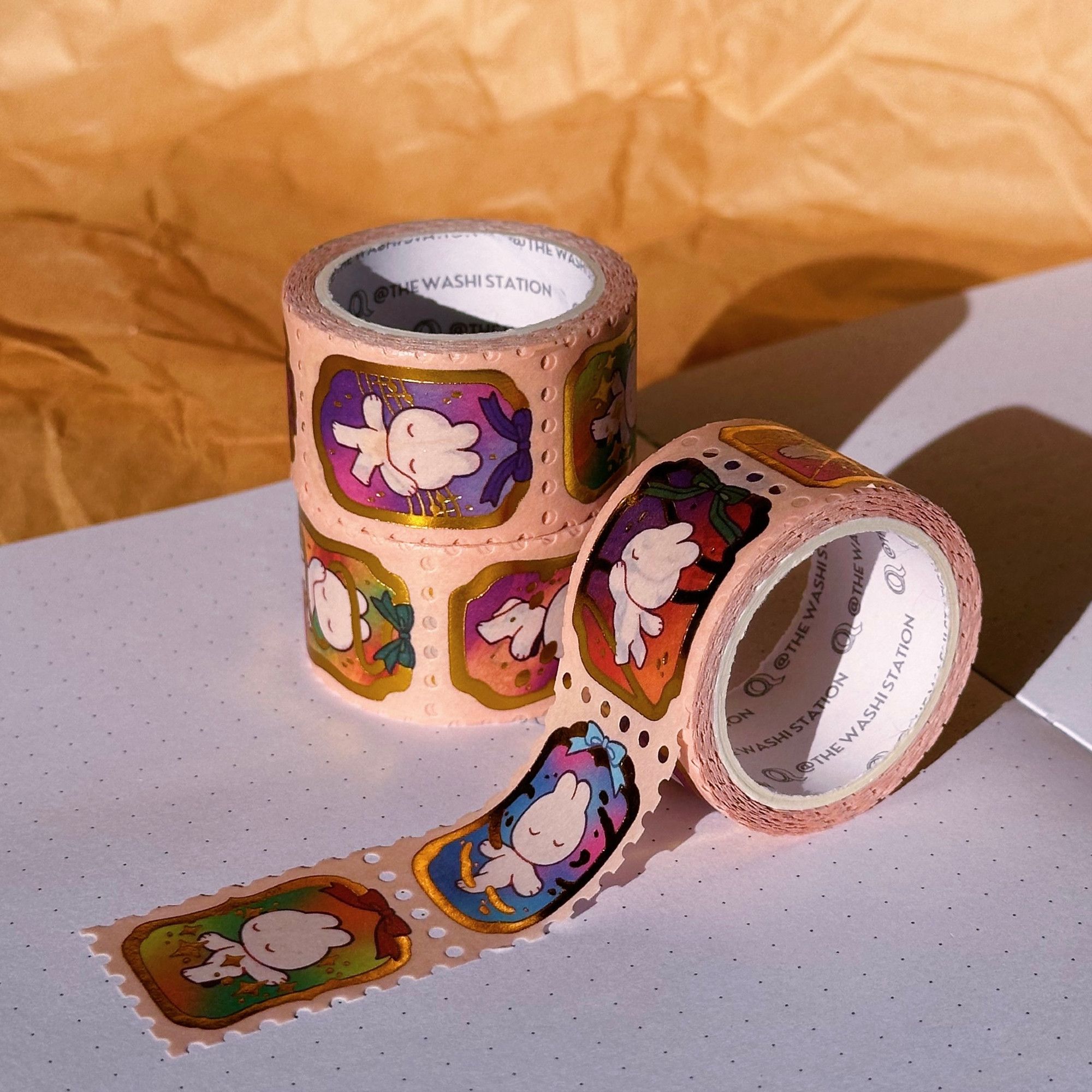 Photo showing a stamp washi tape with gold foil accent called Prism Ballet, depicting a bunny undergoing a rainbow-colored magical transformation.