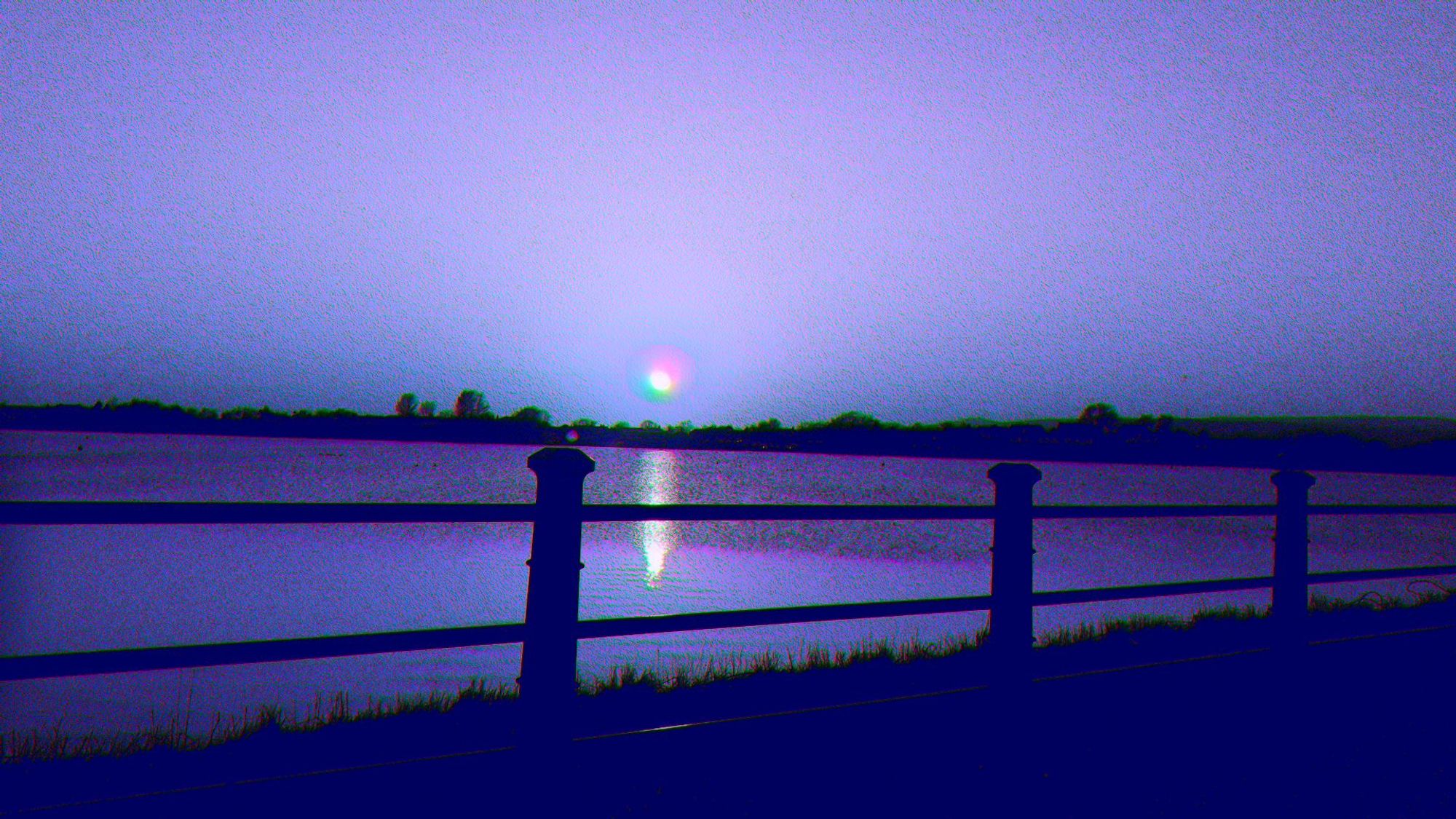 A photograph of a blue sunset, familiar yet alien. The area around the camera is a lakeside view. Created by blending a normal map with the base photograph.