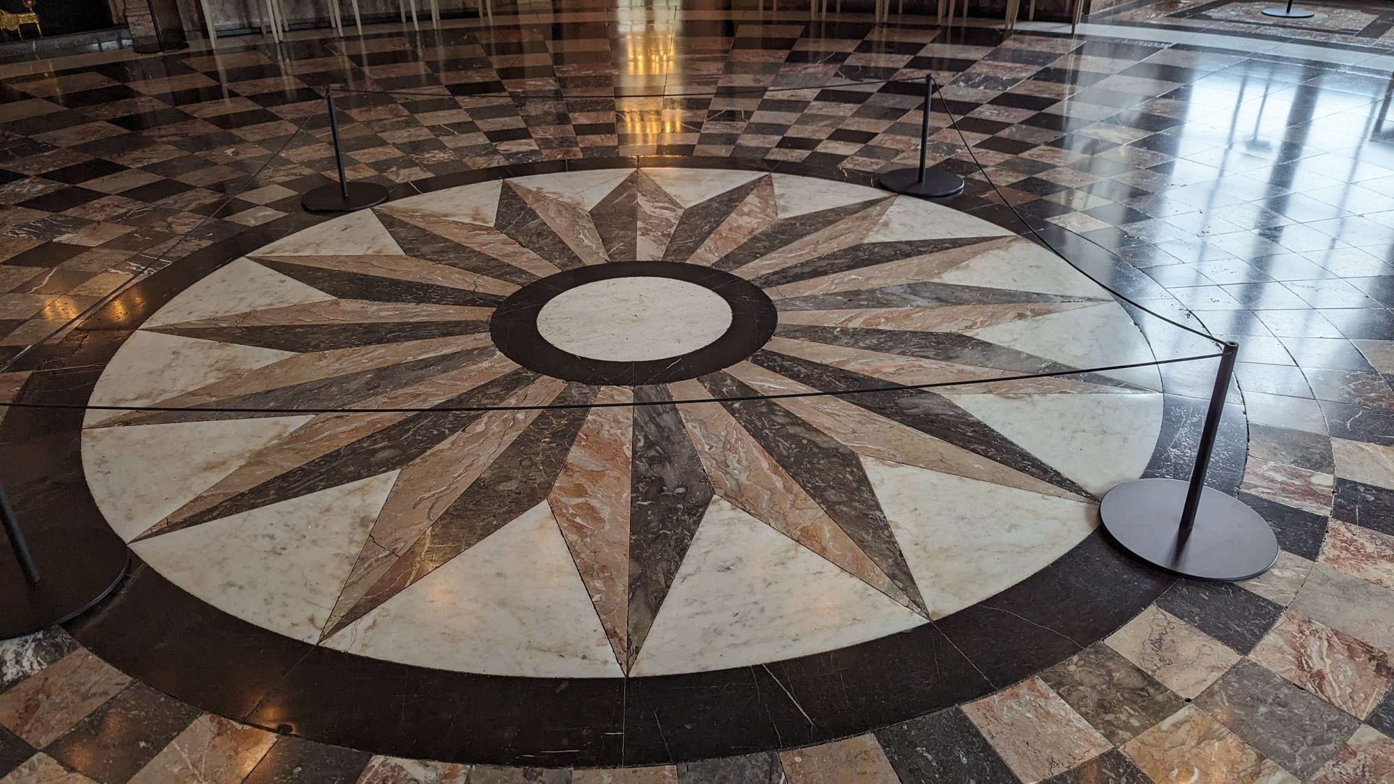 Das Marmorboden in der Schlossrotunde bei dem Spiegelsaal von Schloss Benrath. Sternförmiges Muster im Boden. Licht spiegelt sich darin.