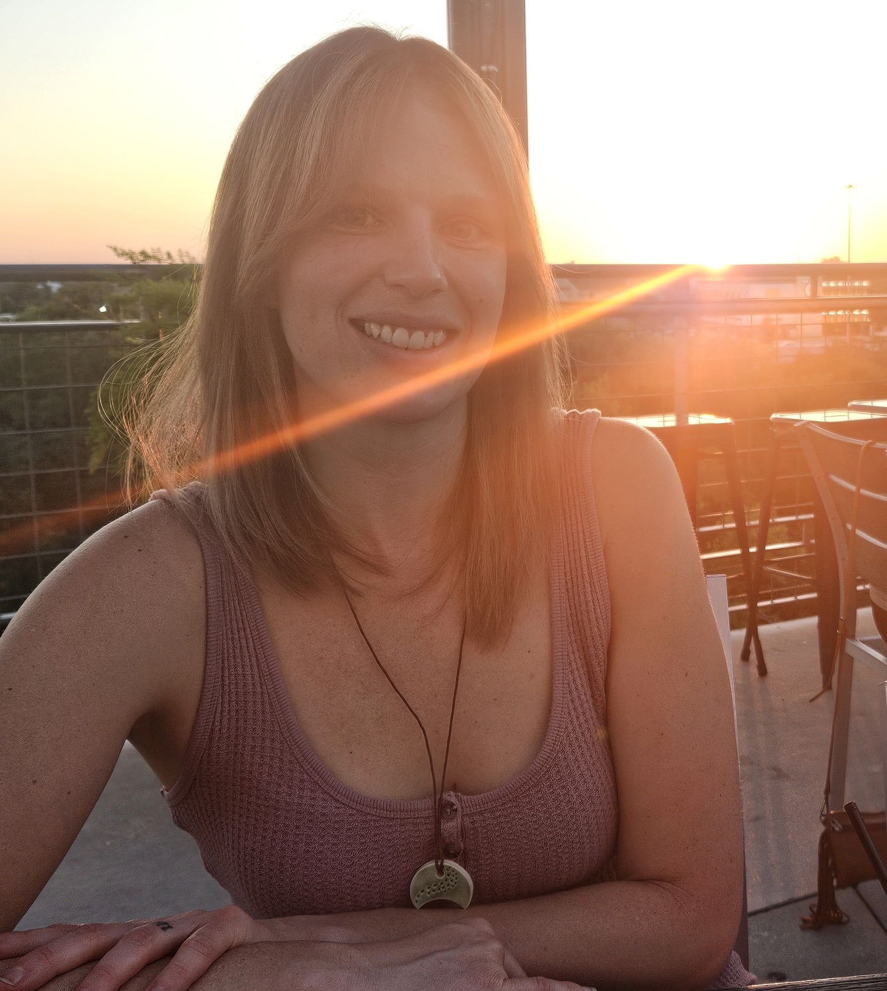 A lovely woman sits in the sunset in a mauve dress