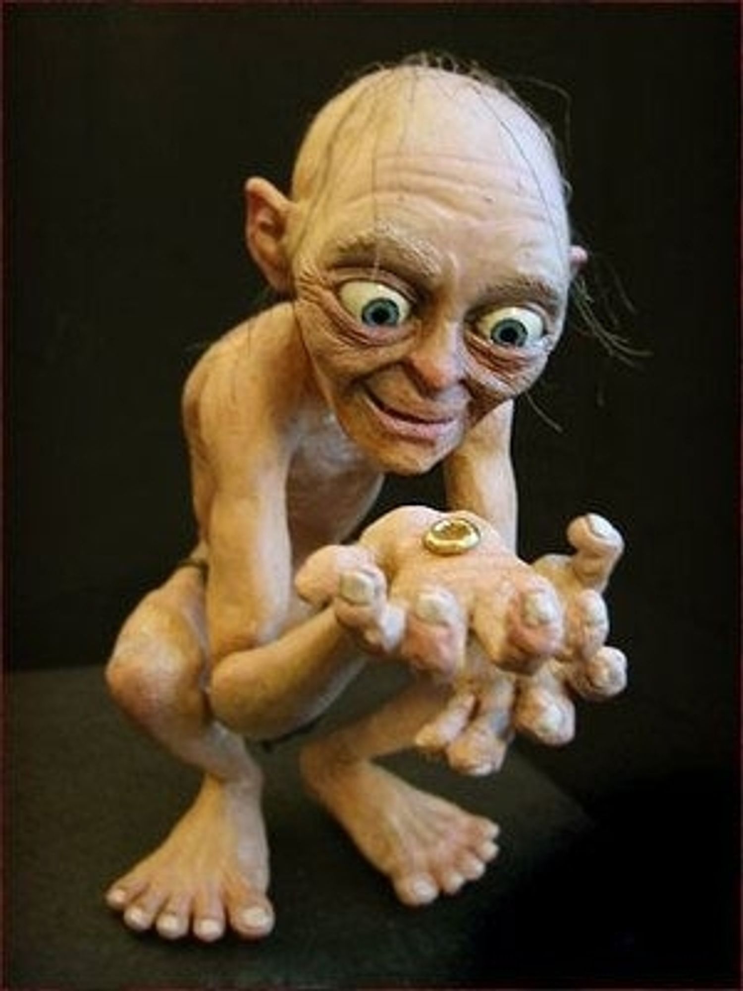 Gollum holding the ring in his hand and looking at it with a happy face