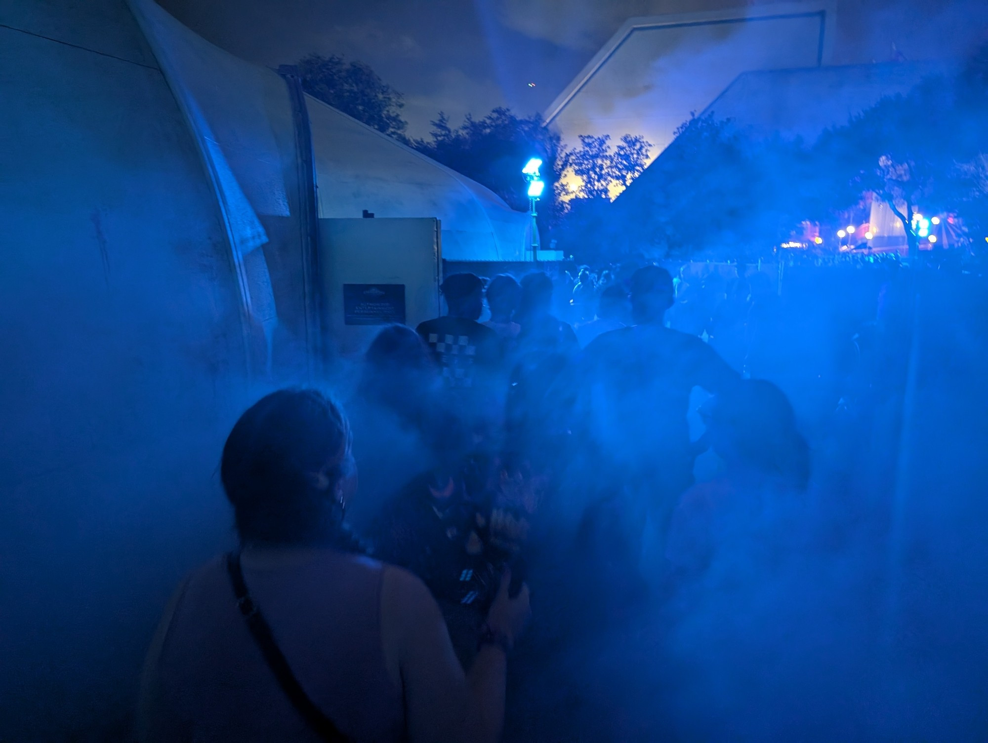 The image shows the line to enter a haunted house. Fog fills the air and casts everything in an opaque blue color.