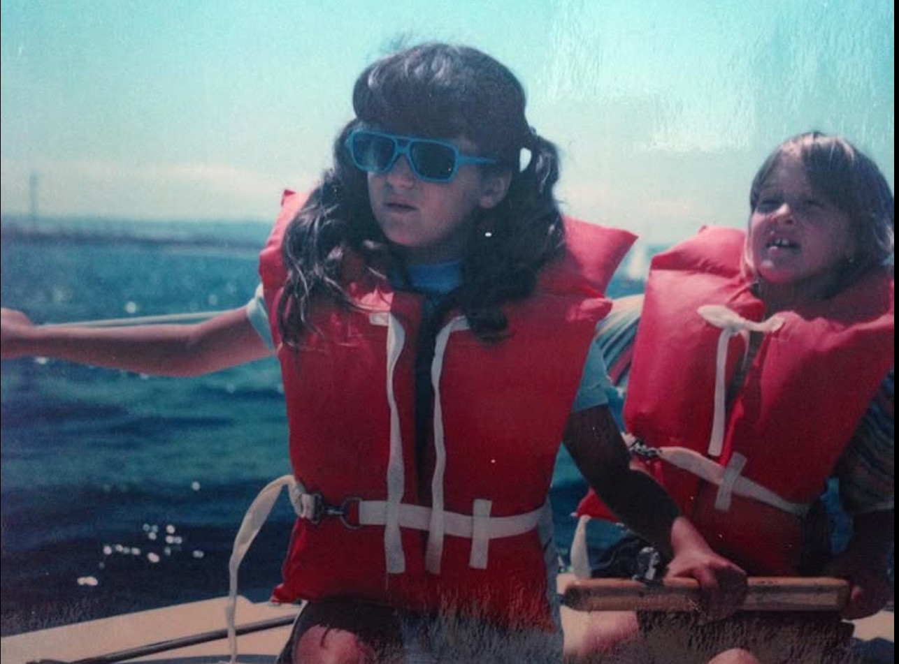 A photo of me on the tiller of my family sailboat, with a friend behind me. I was maybe 10 at the time.