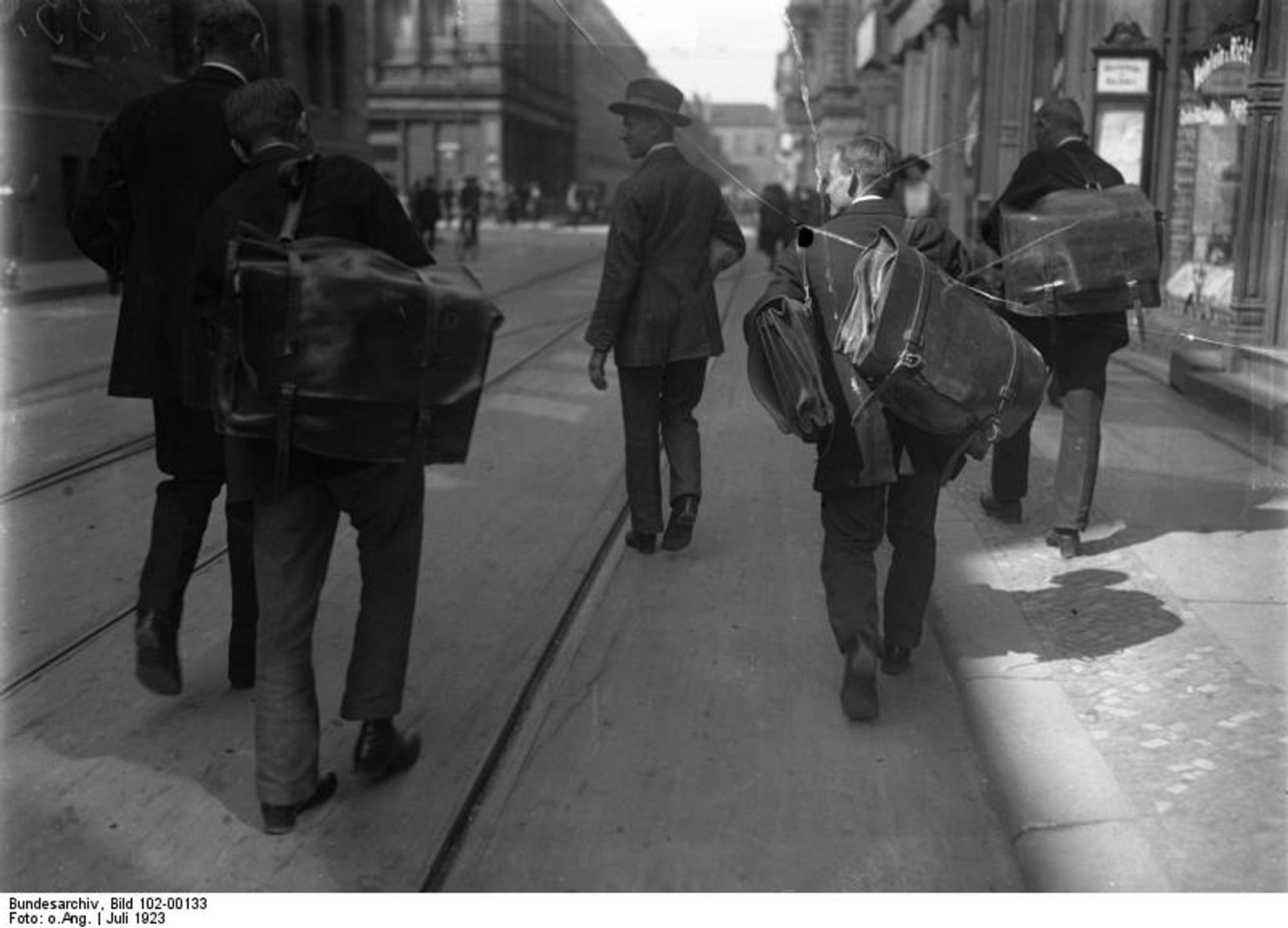 Geldtransport mit Taschen, 1923. Mit grossen Ledertaschen holen Angestellte einer Grossbank unter Bewachung von Kriminalbeamten hohe Werte von der Reichsbank und gehen eine Straße entlang. Nachweis von wiki commons folgt