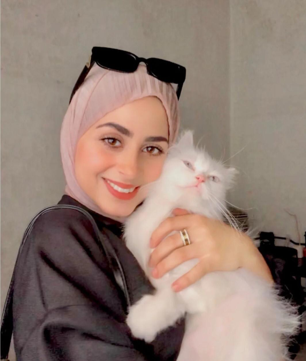 Aseel smiling with a fluffy cat and looking healthy 