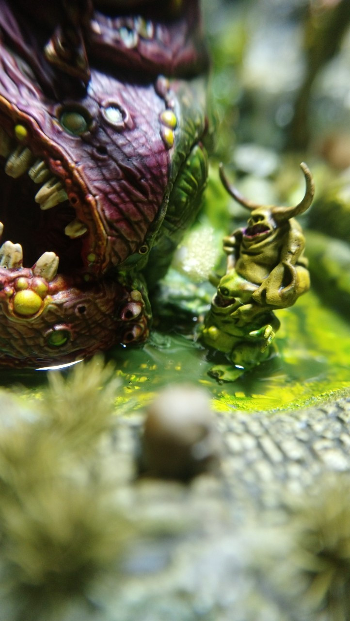 Close-up photo of two Nurglings piled upon each other. The one on the top is holding a sponge and rubbing it against the flank of a Beast of Nurgle.