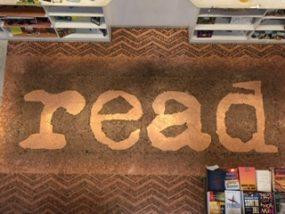 The floor of Little Shop of Stories in Decatur GA, covered in pennies, forming the word "read" from lighter pennies, contrasted with darker pennies around it.