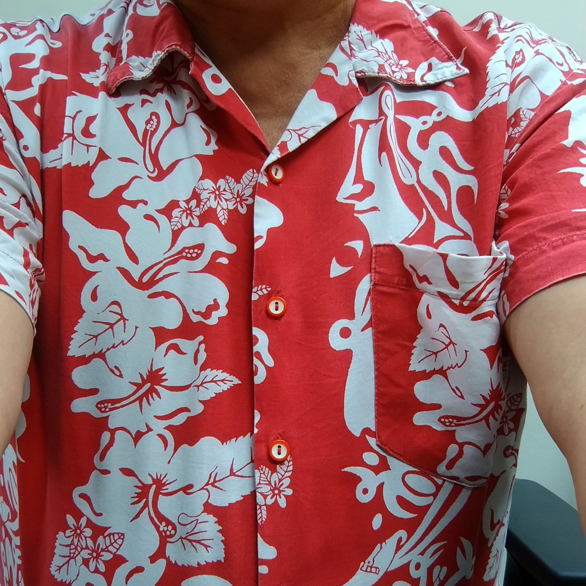 Camisa de manga corta, roja, con flores y figuras de la isla de Pascua.