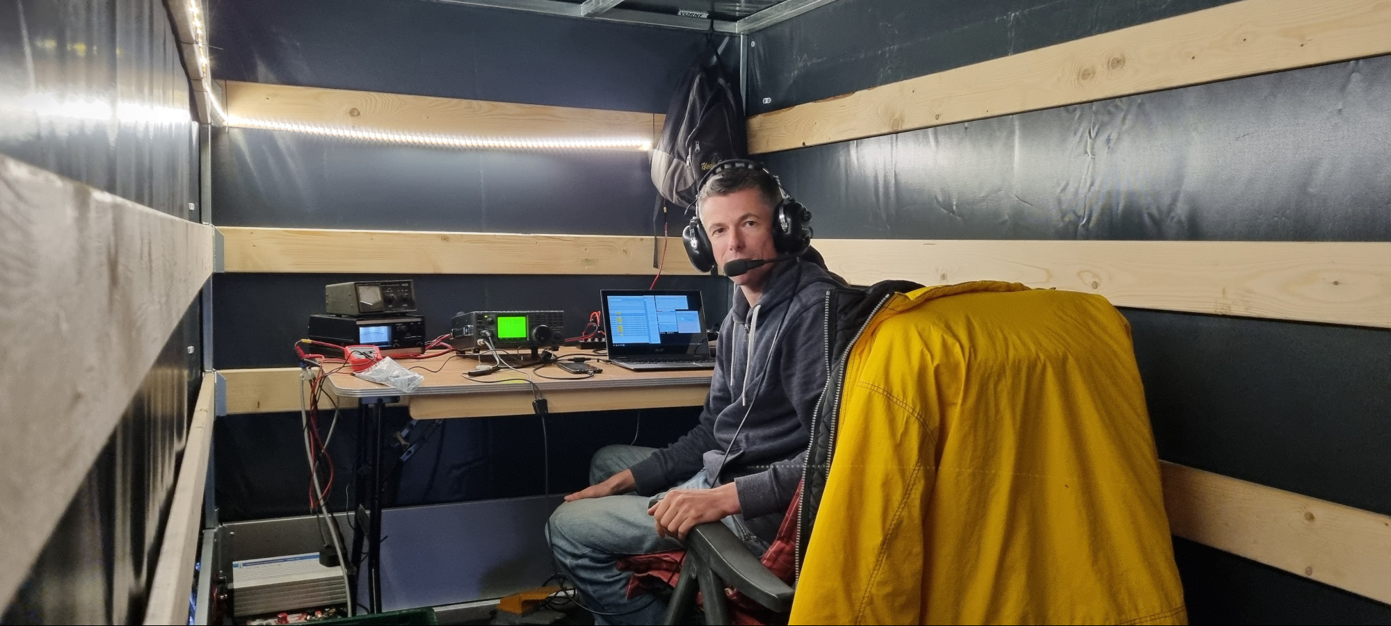 Gerrit sitzt im Anhänger vor dem Tisch mit Rotorsteuerung, Funkgerät und Notebook drauf