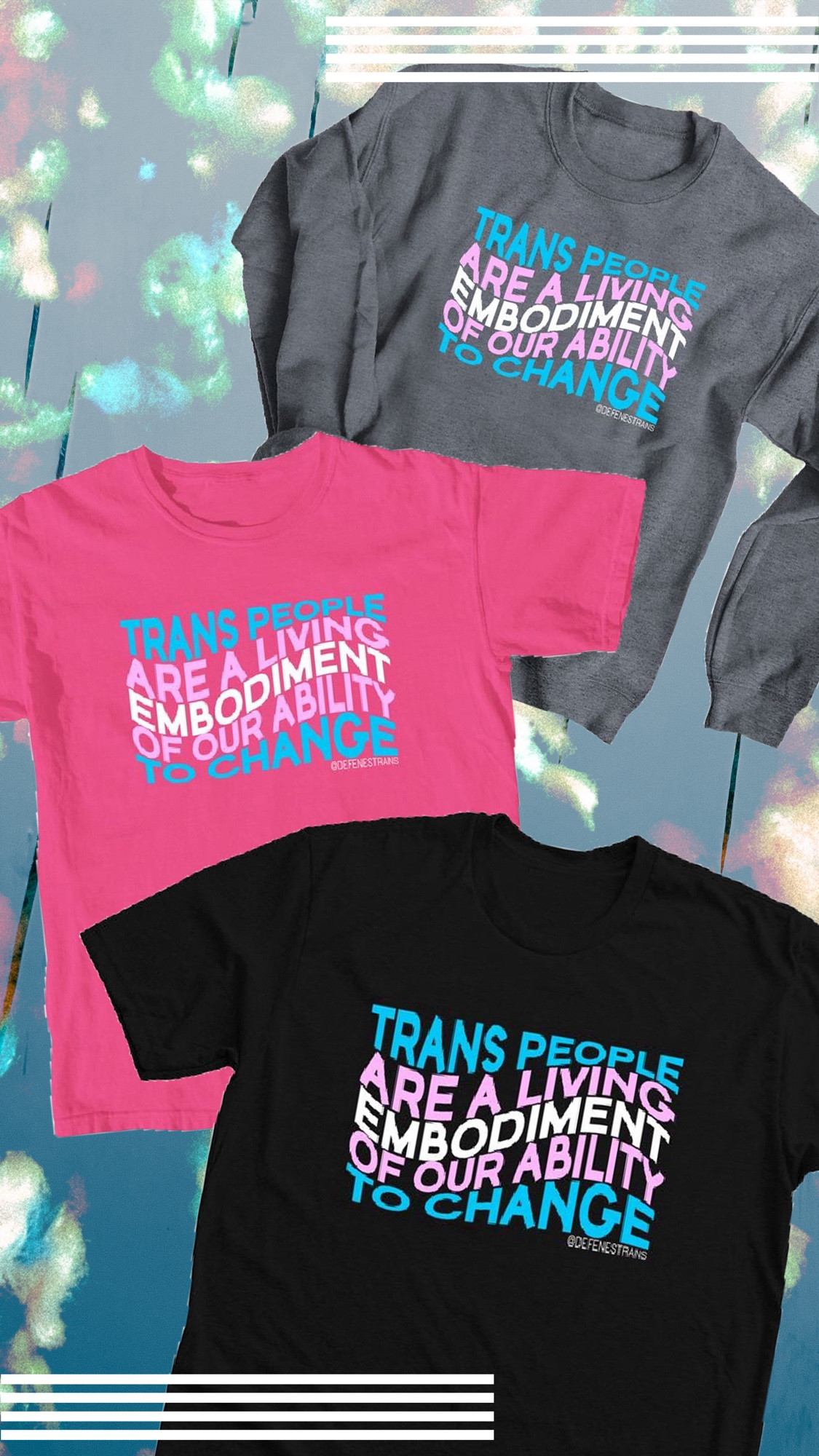 Three t-shirts on a cloudy blue background, one black, one pink, and one gray. They all have the same pink, white, and blue text in a wavy pattern meant to resemble the trans flag. The text reads “Trans people are a living embodiment of our ability to change”