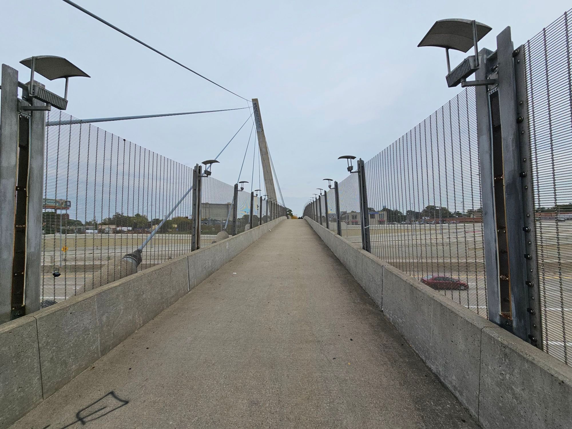 Looking down an empty pedestrian bridge over several lanes of highway