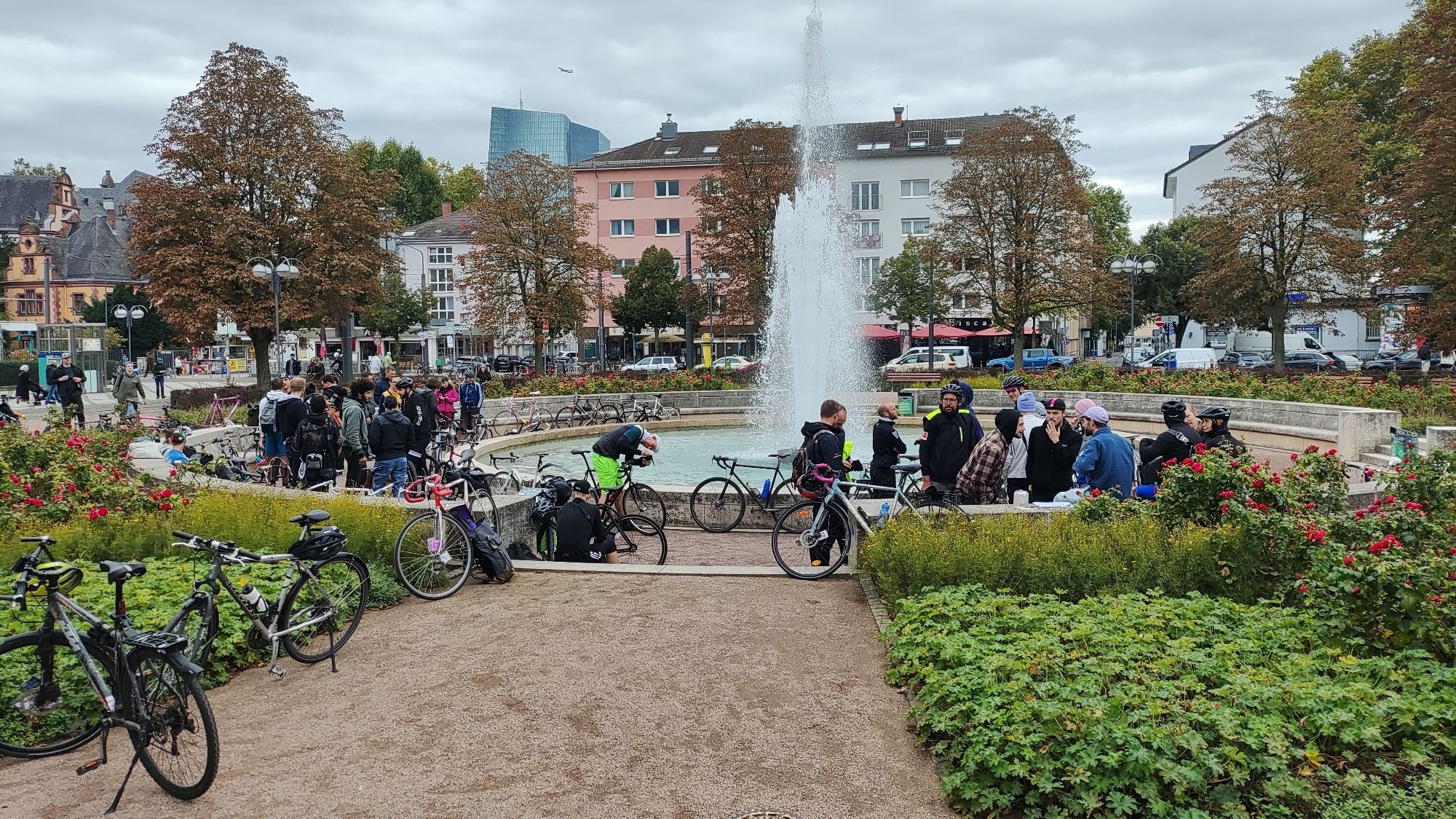 Personen mit Fahrrädern an einem Brunnen