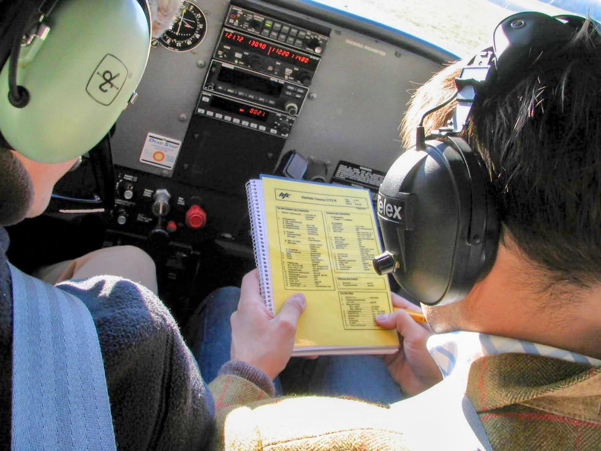 Person mit gr0ßen Kopfhörern auf in der Hand eine checkliste auf gelben Papier. Im Hintergrund Instrumente mit roten Digitalanzeigen