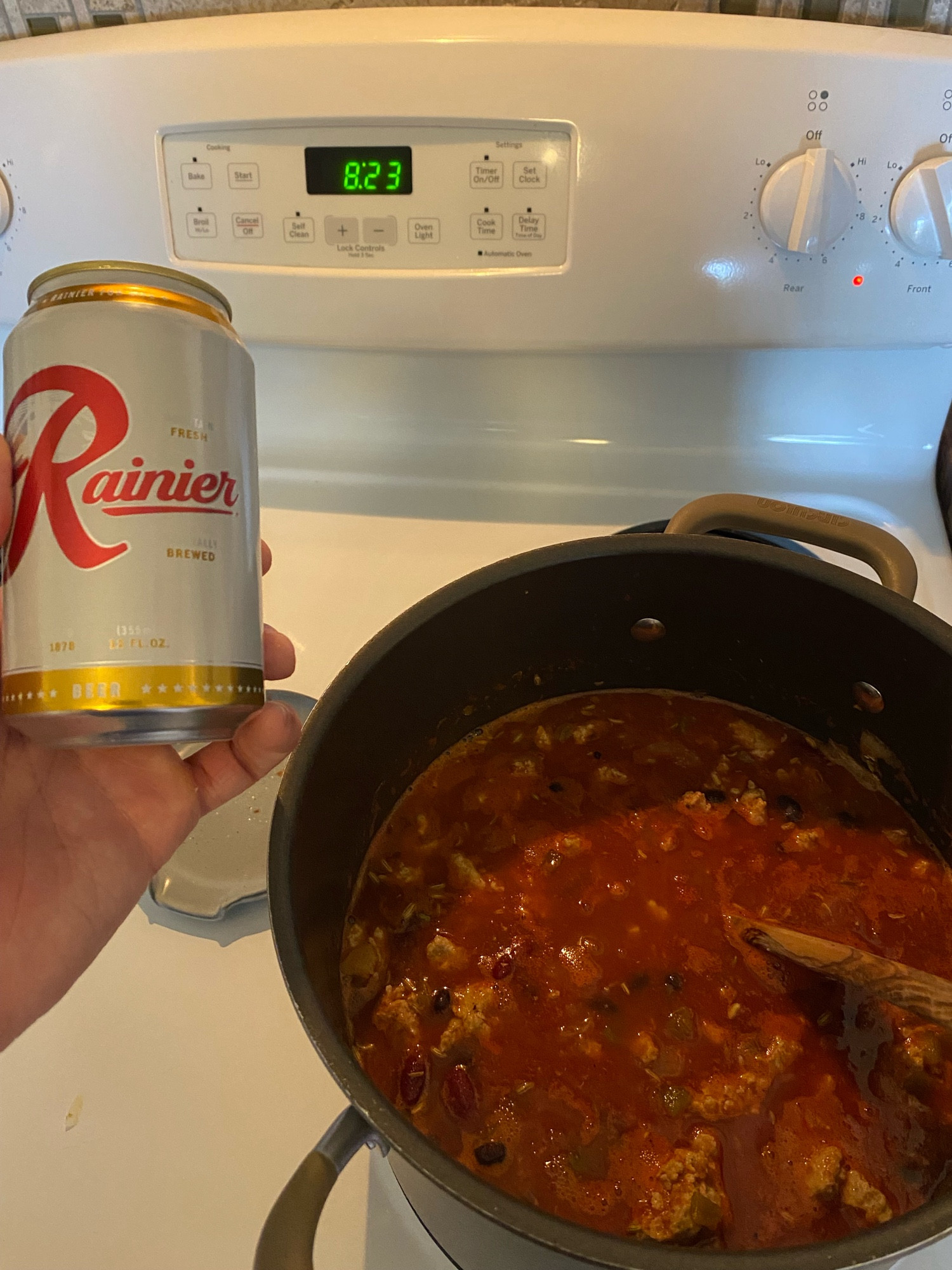 Someone holding a beer with a pot of chili. It is 823 am