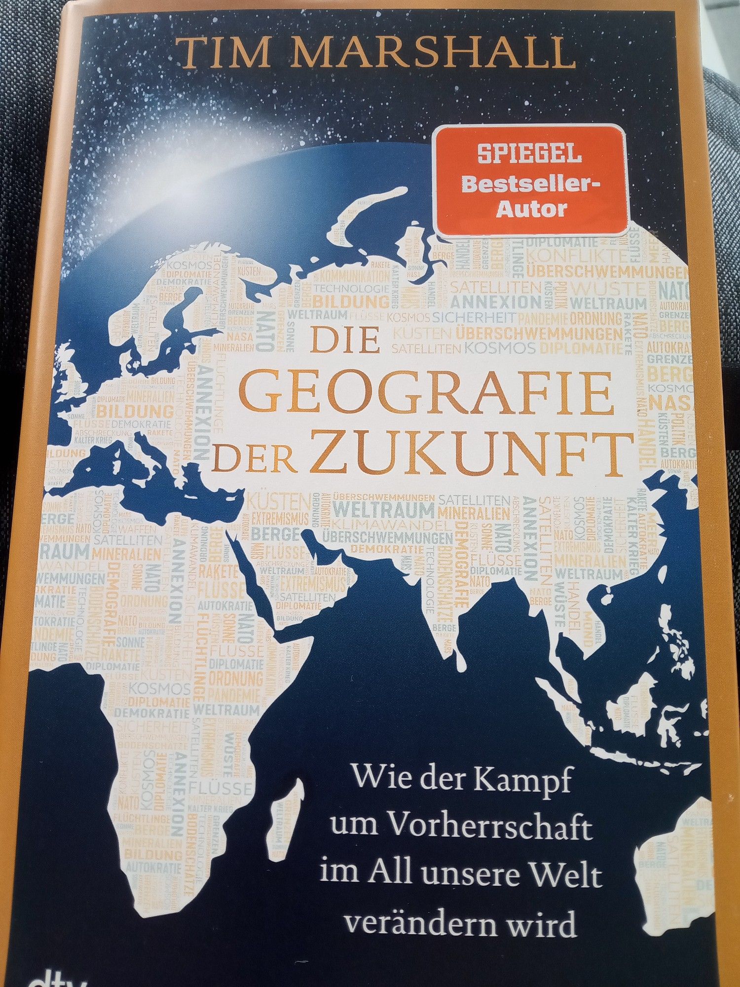 Cover des Buches: Tim Marshall: Die Geografie der Zukunft. Wie der Kampf um Vorherrschaft im All unsere Welt verändern wird, darauf eine schematische Weltkugel, darin die Umrisse der Kontinente Europa, Afrika, Asien und Australien, gefüllt mit einer Tagcloud