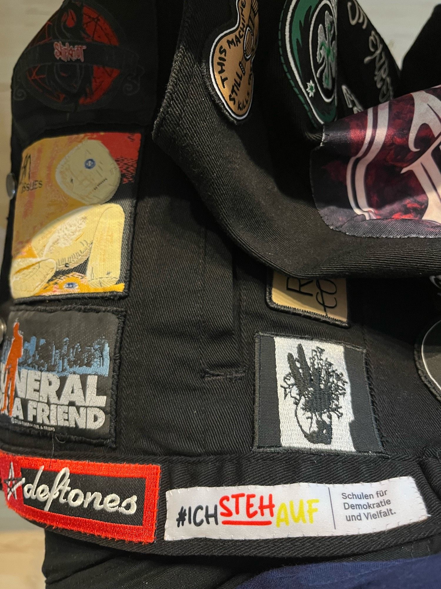 Metalkutte mit verschiedenen Patches und einem weißen Aufnäher am unteren Saum mit der Aufschrift #ichstehauf in schwarz rot gelb und daneben in schwarzer Schrift „Schulen für Demokratie und Vielfalt“