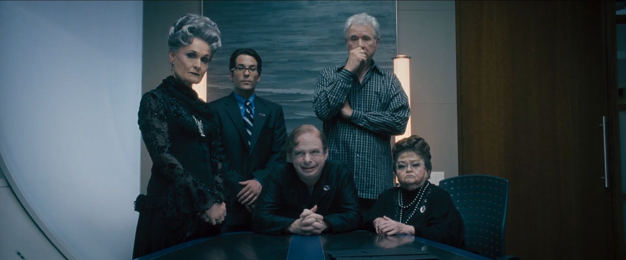 'Southland Tales' (2006) Two old women and three men, dressed in dark colors, looking at the camera, sitting on a conference table.