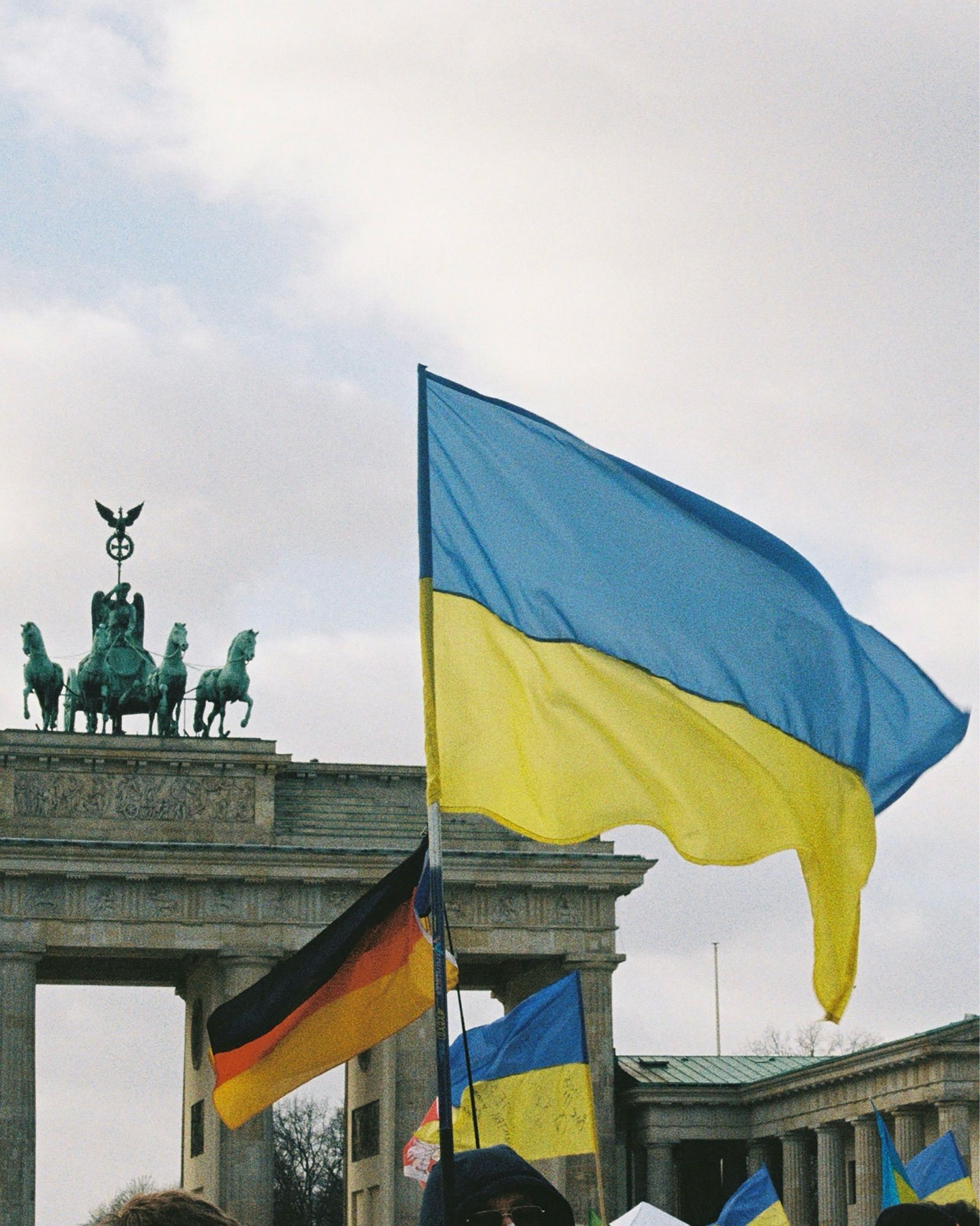 Ein Bild des Brandenburger Tors. Im Vordergrund eine ukrainische Flagge.