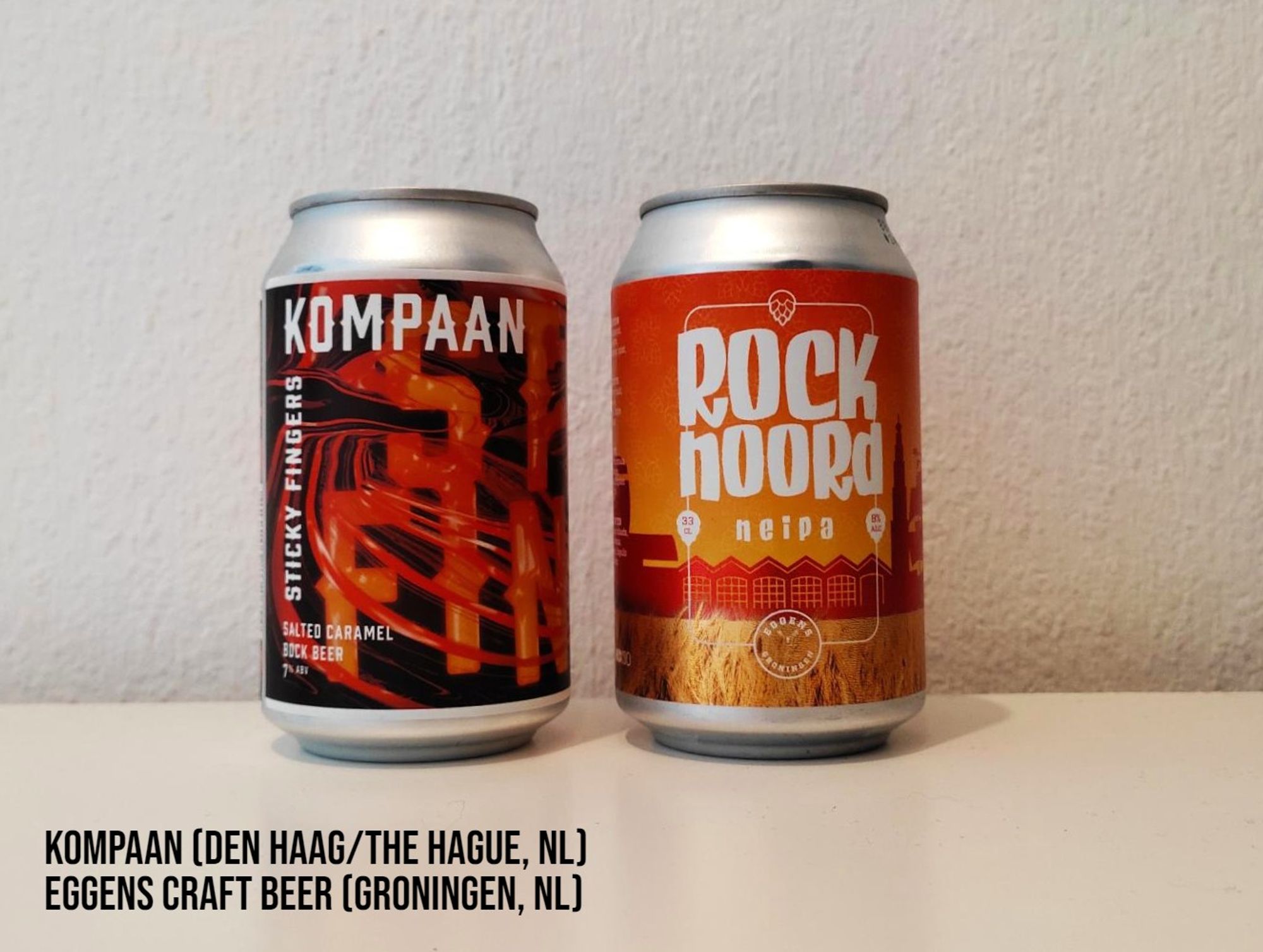 Two 330 ml cans of beer by Kompaan and Eggens breweries from the Netherlands. Both cans are predominantly orange, white and black in color.