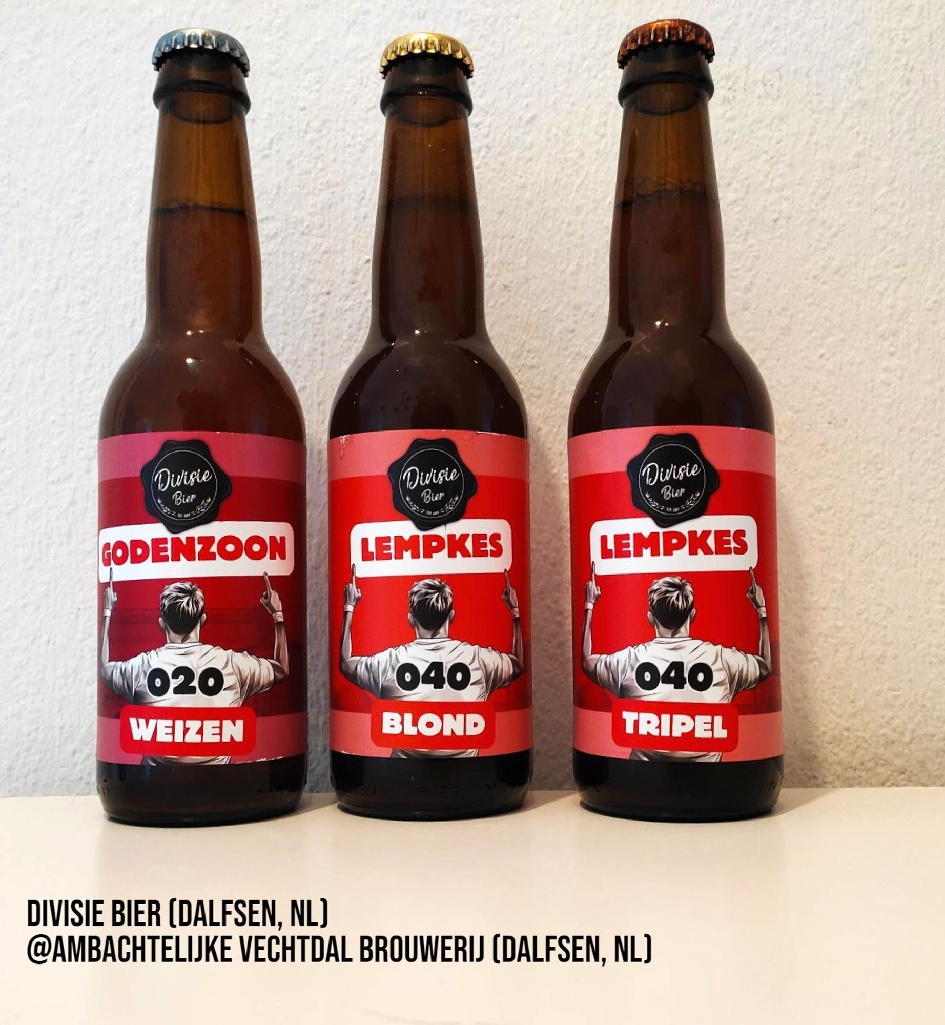 Three 300 ml bottles of beer by Divisie Bier. The labels show a soccer player's back and are done in distinctive colors (burgundy/white for Eindhoven, dark orange/white for Amsterdam)