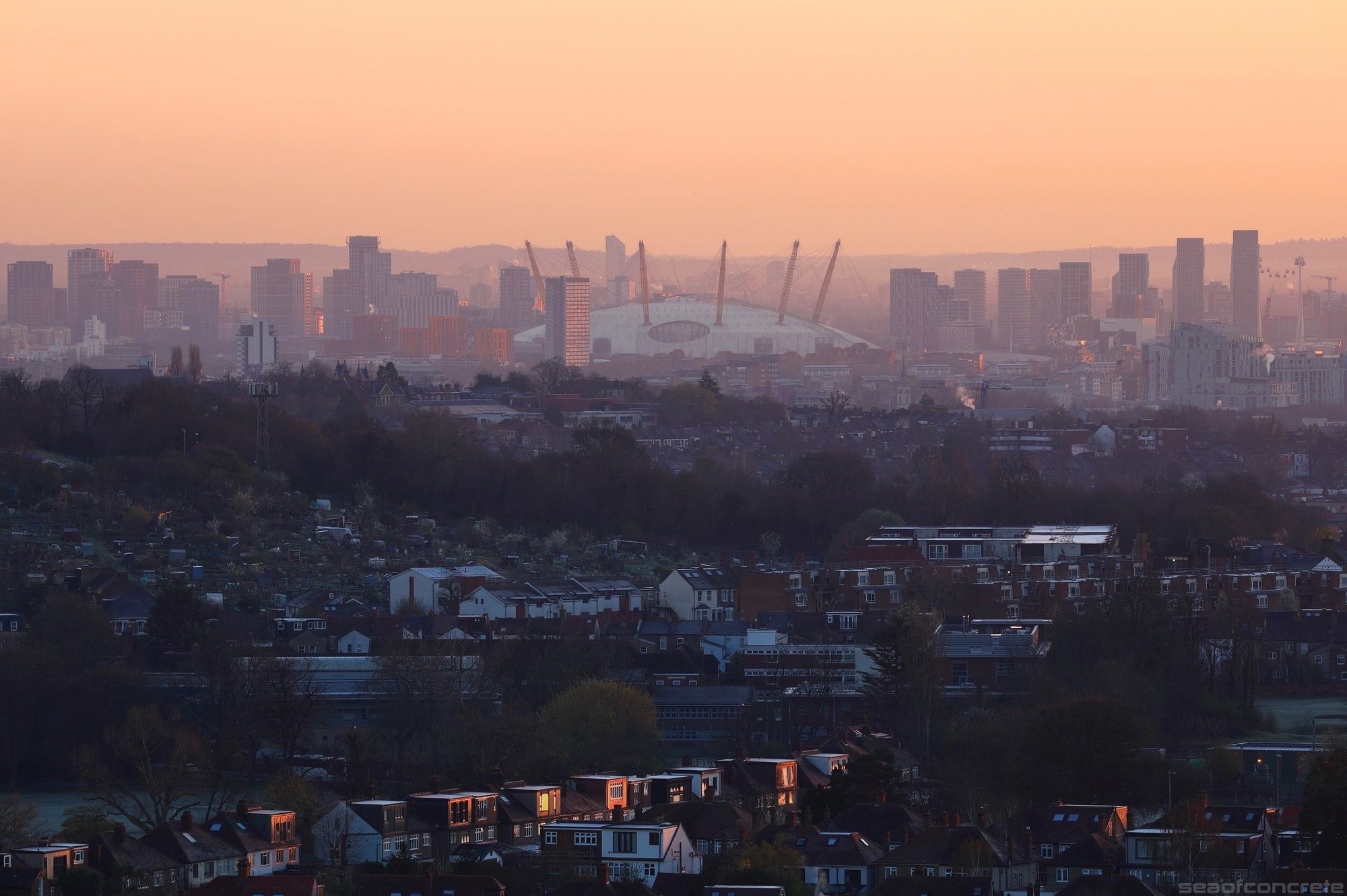 The O2 Arena and the surrounding buildings are illuminated by the rising sun