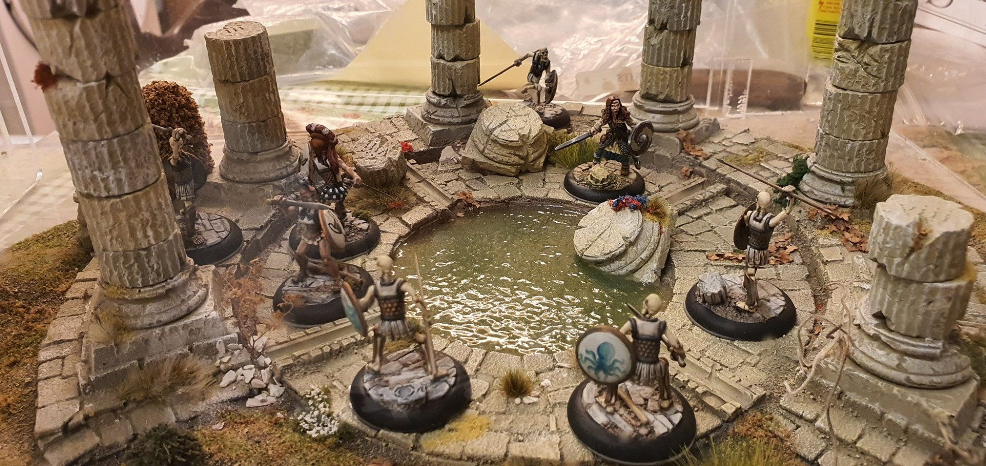 Model shot: skeleton warriors attacking bronze Age adventurers in a ruined temple by a flooded altar.