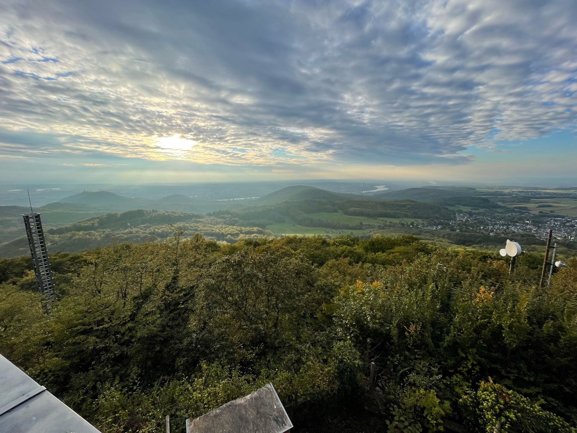 Blick von der Terrasse auf dem Ölberg im Siebengebirge im herbstlich-abendlichen Sonnenlicht mit leicht bewölkten Himmel. Der weite Blick ins Land schweift über Drachenfels und Petersberg über den dahinter fließenden Rhein bis links außen zum Radom in Wachtberg, dem Posttower in Bonn bis außen rechts am Horizont dem Colonius und dem Kölner Dom (wegen der Auflösung nicht mehr zu erkennen).