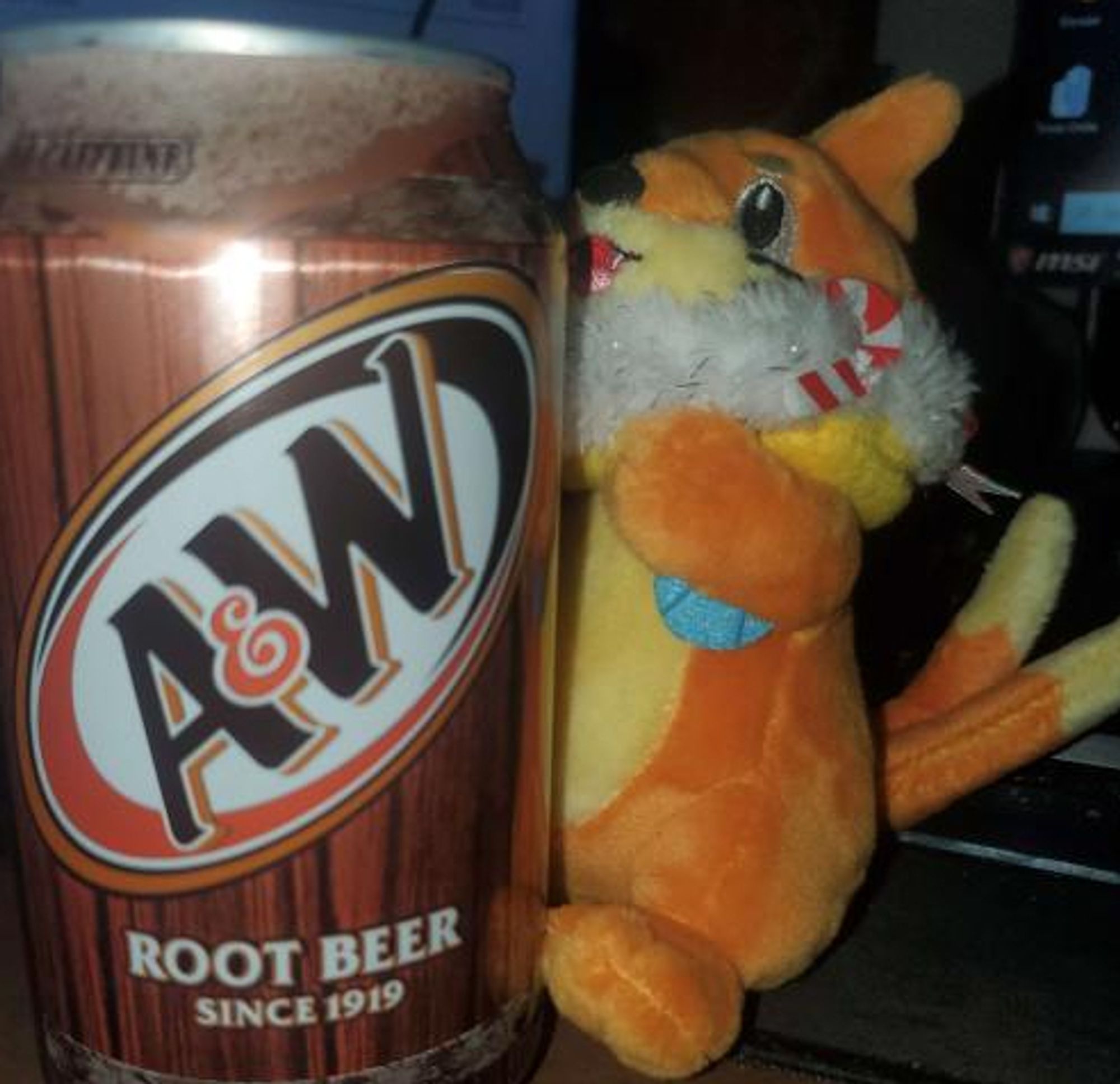 Close-up of a Buizel plushie holding a can of A&W root beer.