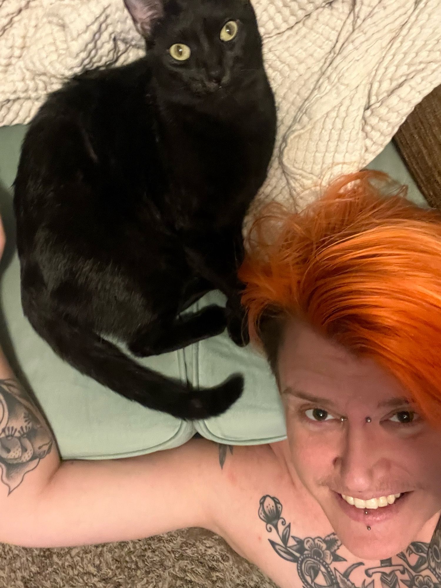 selfie where i’m sitting on the floor and squid is on the couch behind me.  the pov is from above and i’m smiling and squid is looking up at the camera with wide blank eyes