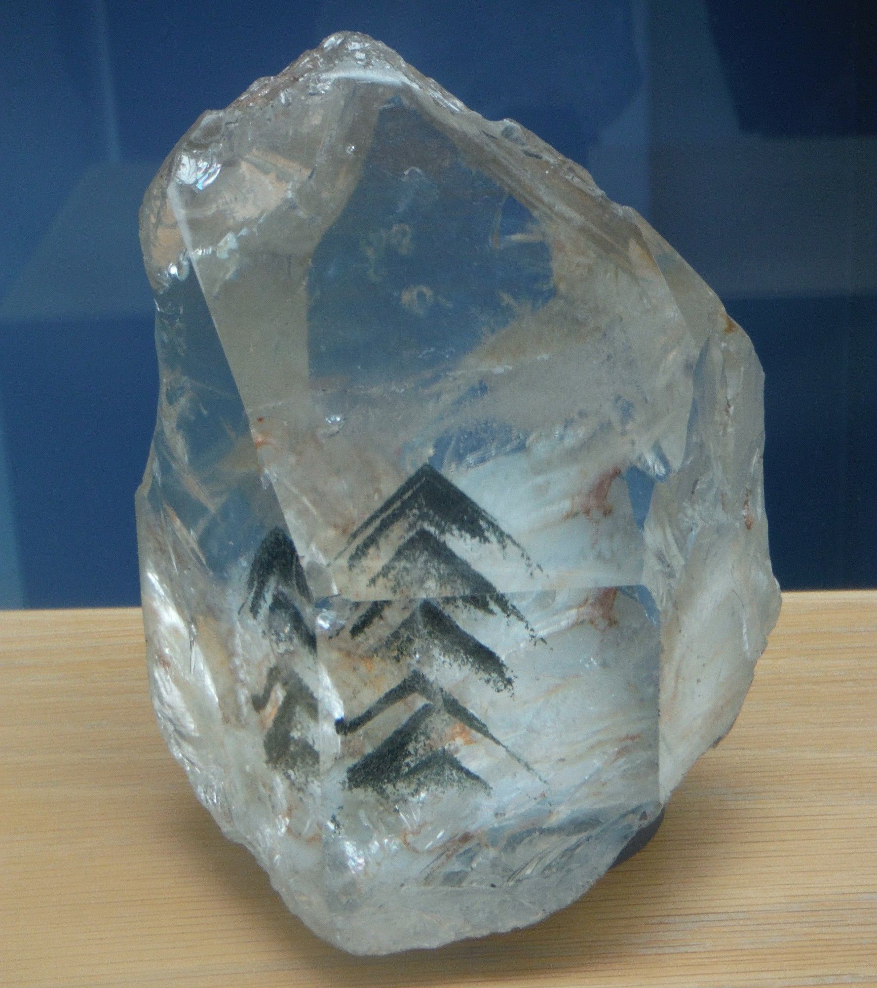 Phantom quartz. A crystal clear prism of quartz with black arrow shaped inclusions inside. On display in the Natural History Museum, London.