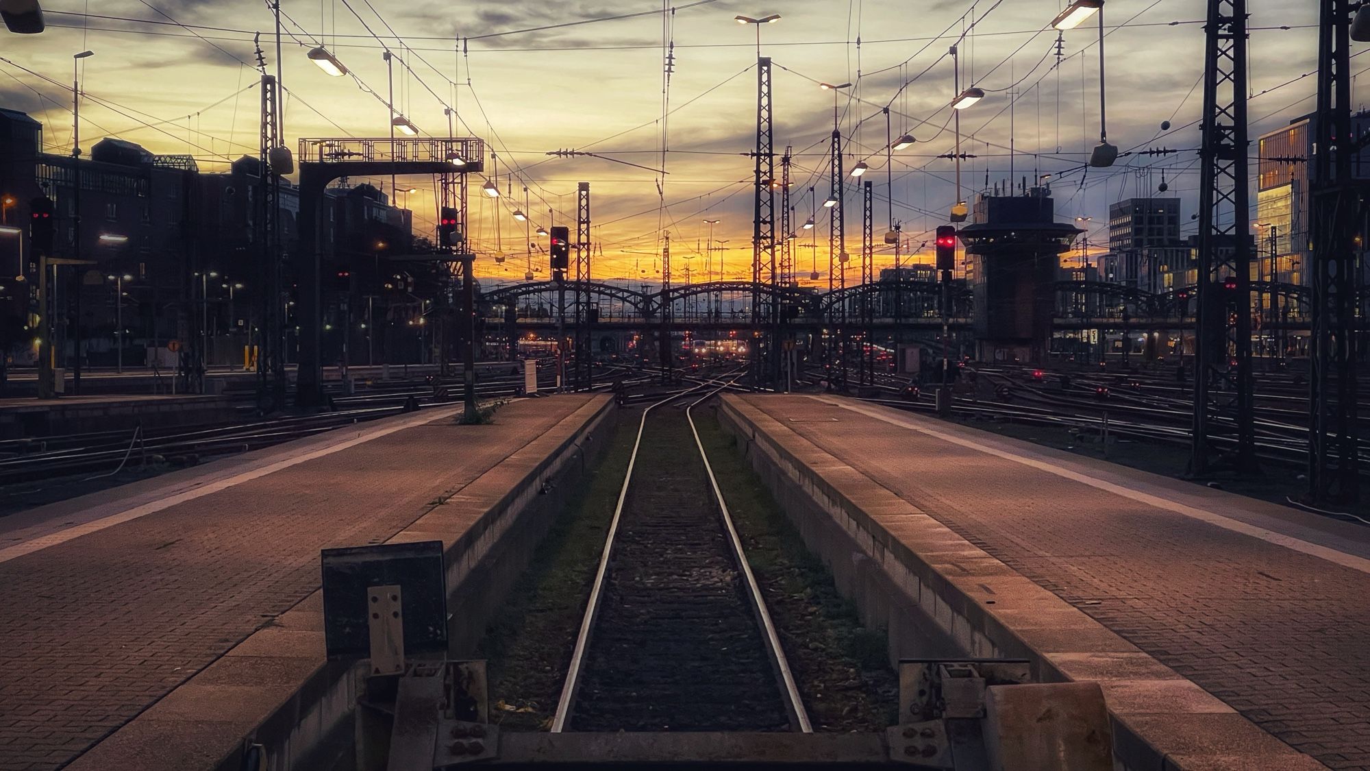 Blick auf Gleise und Bahnsteige des Hauptbahnhofs im goldenen Abendlicht.