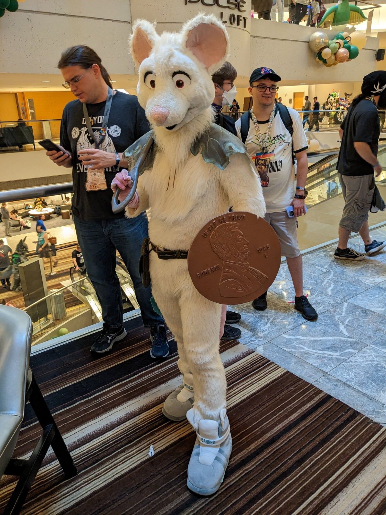 A mouse fursuiter dressed up as a warrior. Holding a sewing needle for a sword and a penny for a shield.