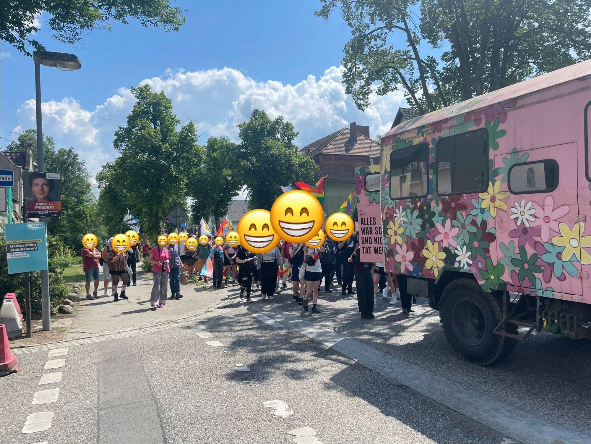 CSD-Demozug auf der Straße in Rheinsberg, vorneweg fährt ein alter LKW mit Kofferaufbau - in rosa und mit Blümchen bemalt.