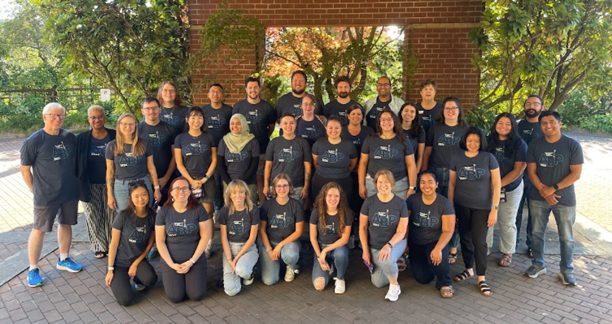 A group photo taken in a courtyard. Everyone is wearing a matching Academy of Best Practices t-shirt.