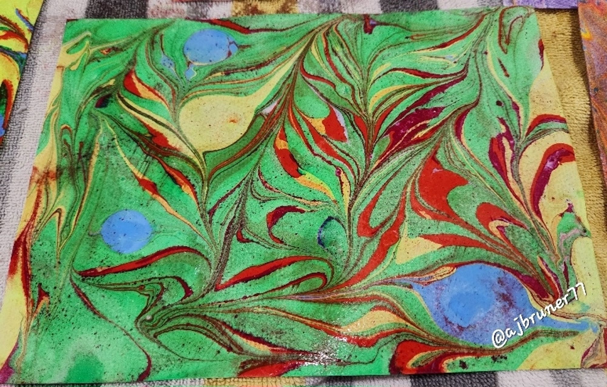 Sample paint marbling with red, green, and yellow swirls and feather-shapes for #ColoringTherapy.