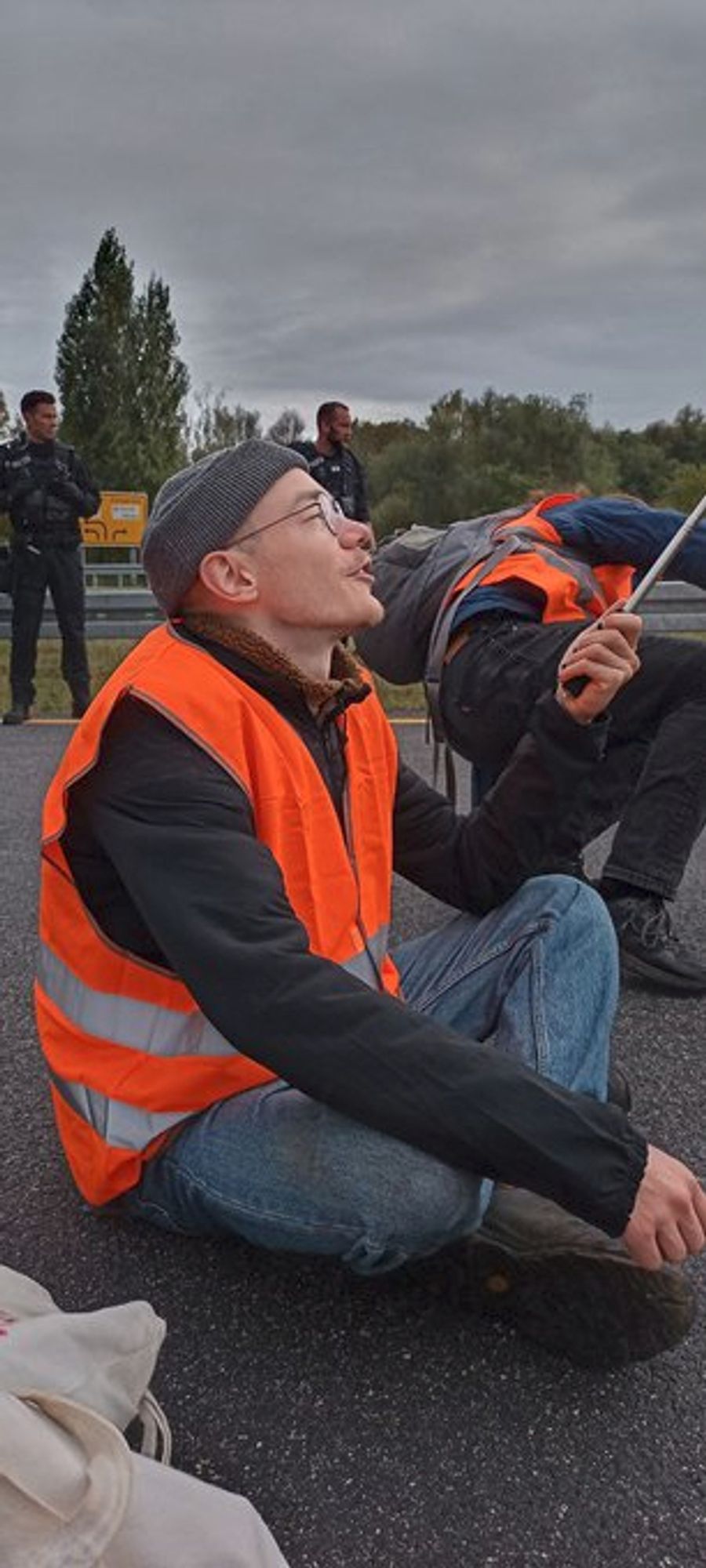 Mensch in orangener Warnweste hält Flagge hoch